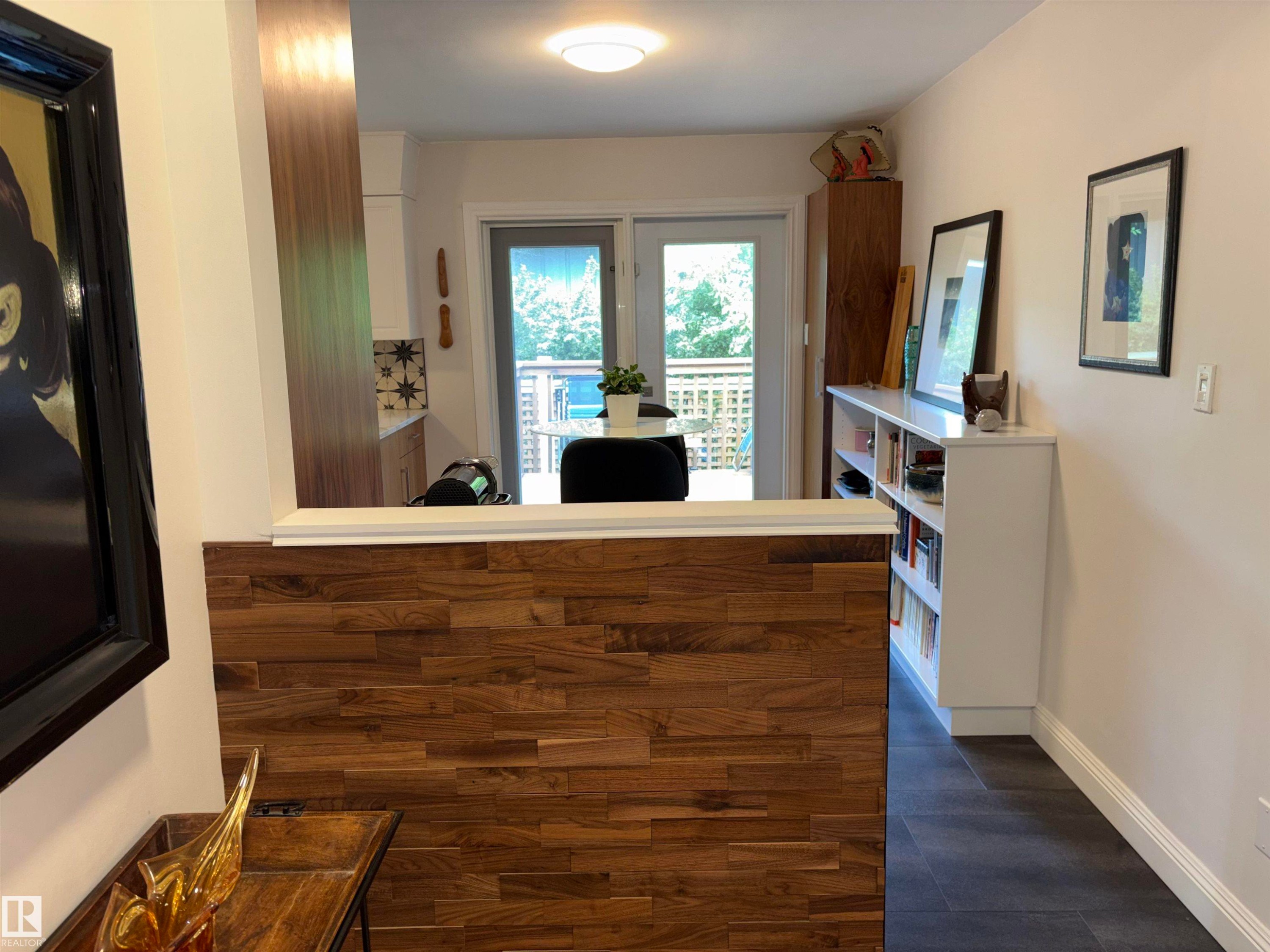 Kitchen with wood-finish flooring, white built-in shelving, and a glass-paneled door opening to a deck - 14016 85 Avenue Nw, Edmonton, AB - Indoor Photo Showing Other Room