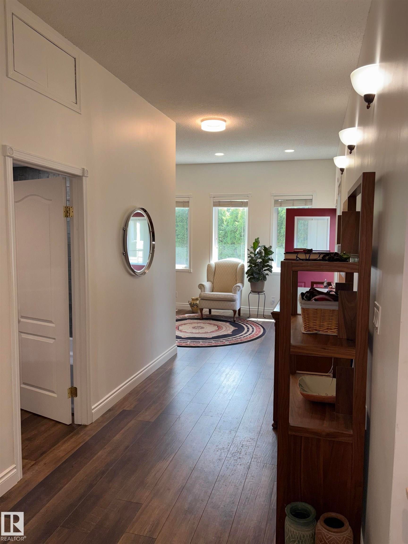 Expansive entryway featuring wood-finish flooring, white baseboards, and a series of wall sconces - 14016 85 Avenue Nw, Edmonton, AB - Indoor Photo Showing Other Room