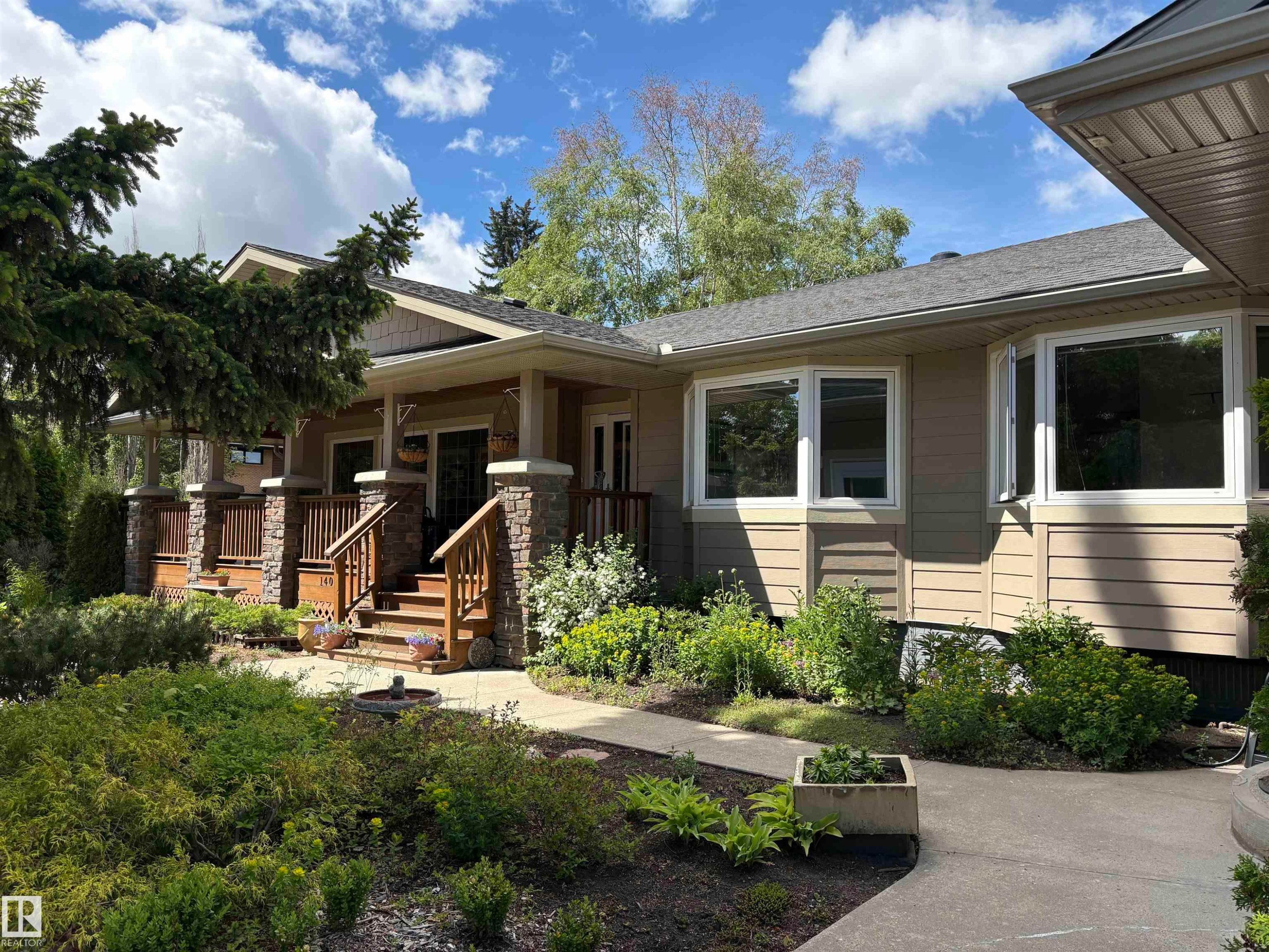 Craftsman-style exterior featuring a covered porch with stone-clad columns and wood railings - 14016 85 Avenue Nw, Edmonton, AB - Outdoor