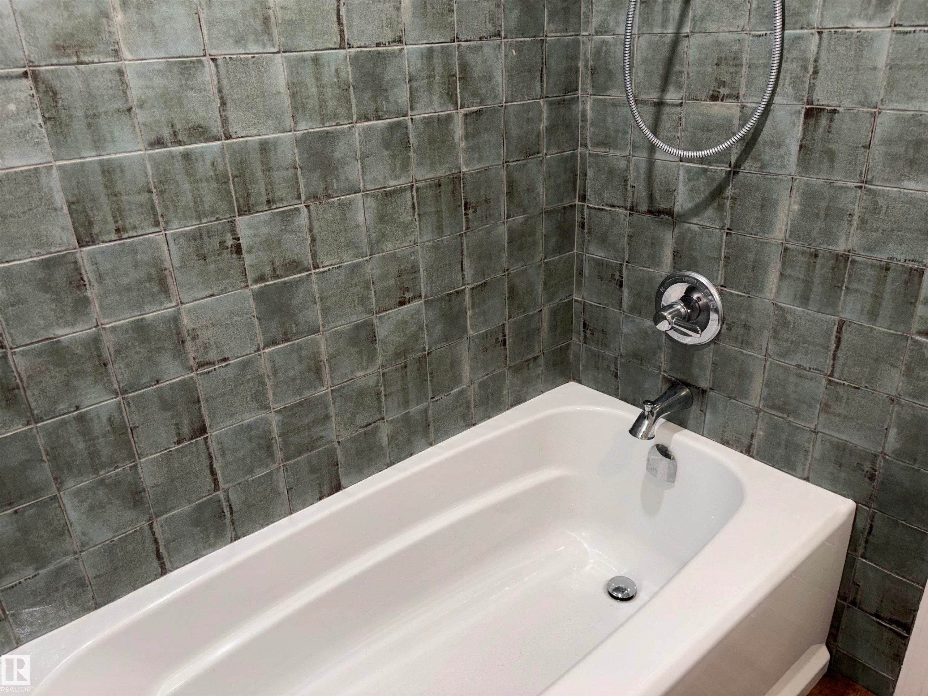 White bathtub with chrome fixtures and square-patterned wall tiling - 14016 85 Avenue Nw, Edmonton, AB - Indoor Photo Showing Bathroom