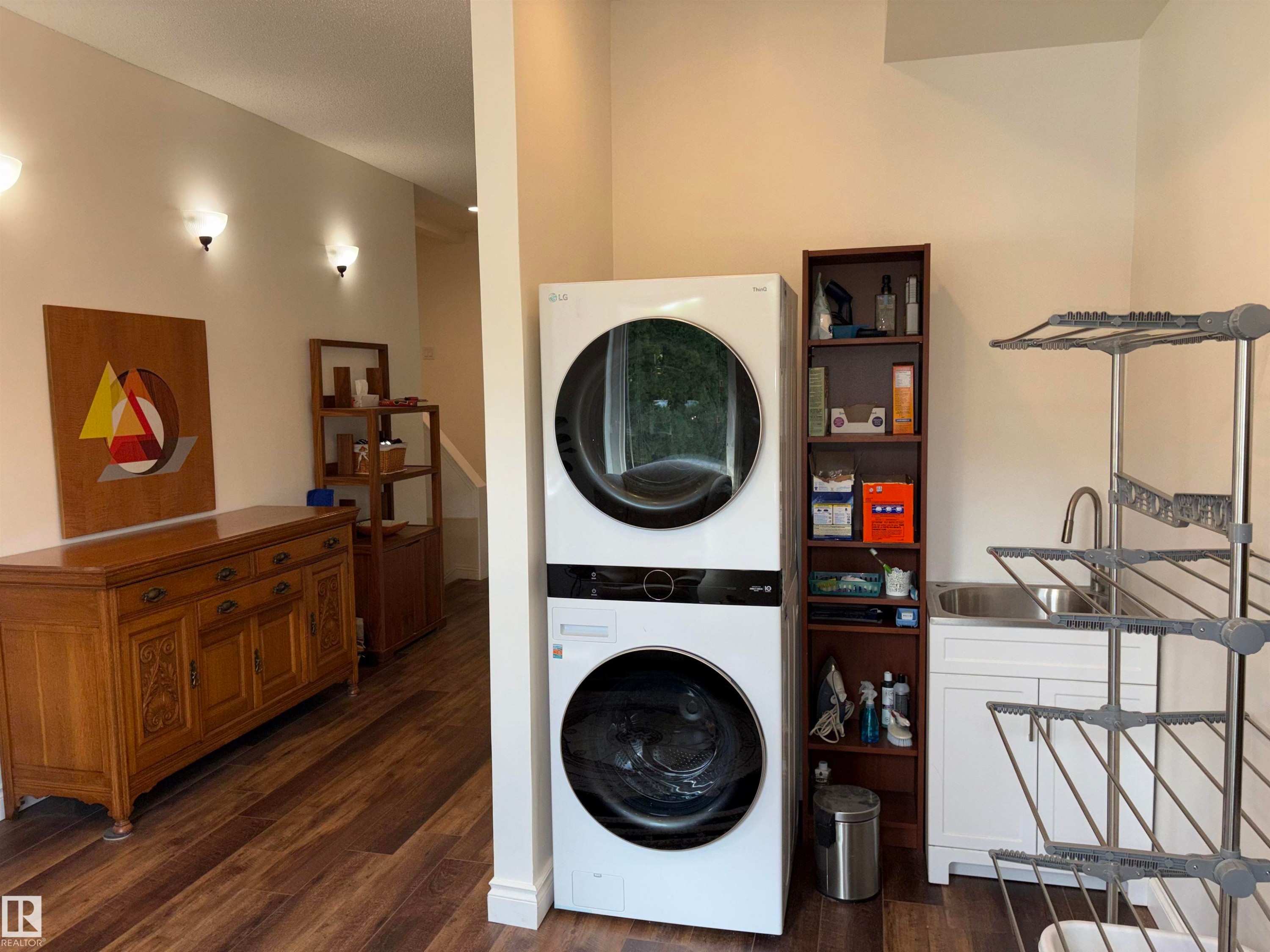 Dedicated laundry area featuring stacked front-load machines, a utility sink with a high-arc faucet, and built-in white cabinetry - 14016 85 Avenue Nw, Edmonton, AB - Indoor Photo Showing Laundry Room