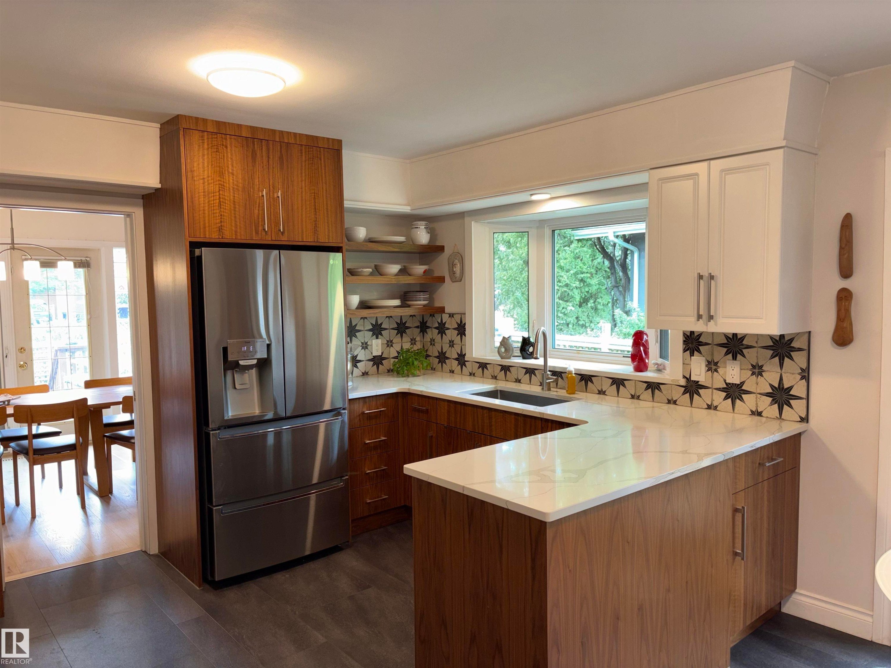 Modern kitchen featuring a stainless steel refrigerator, white countertops, wood-finish lower cabinetry, white upper cabinetry, and a patterned tile backsplash - 14016 85 Avenue Nw, Edmonton, AB - Indoor Photo Showing Kitchen
