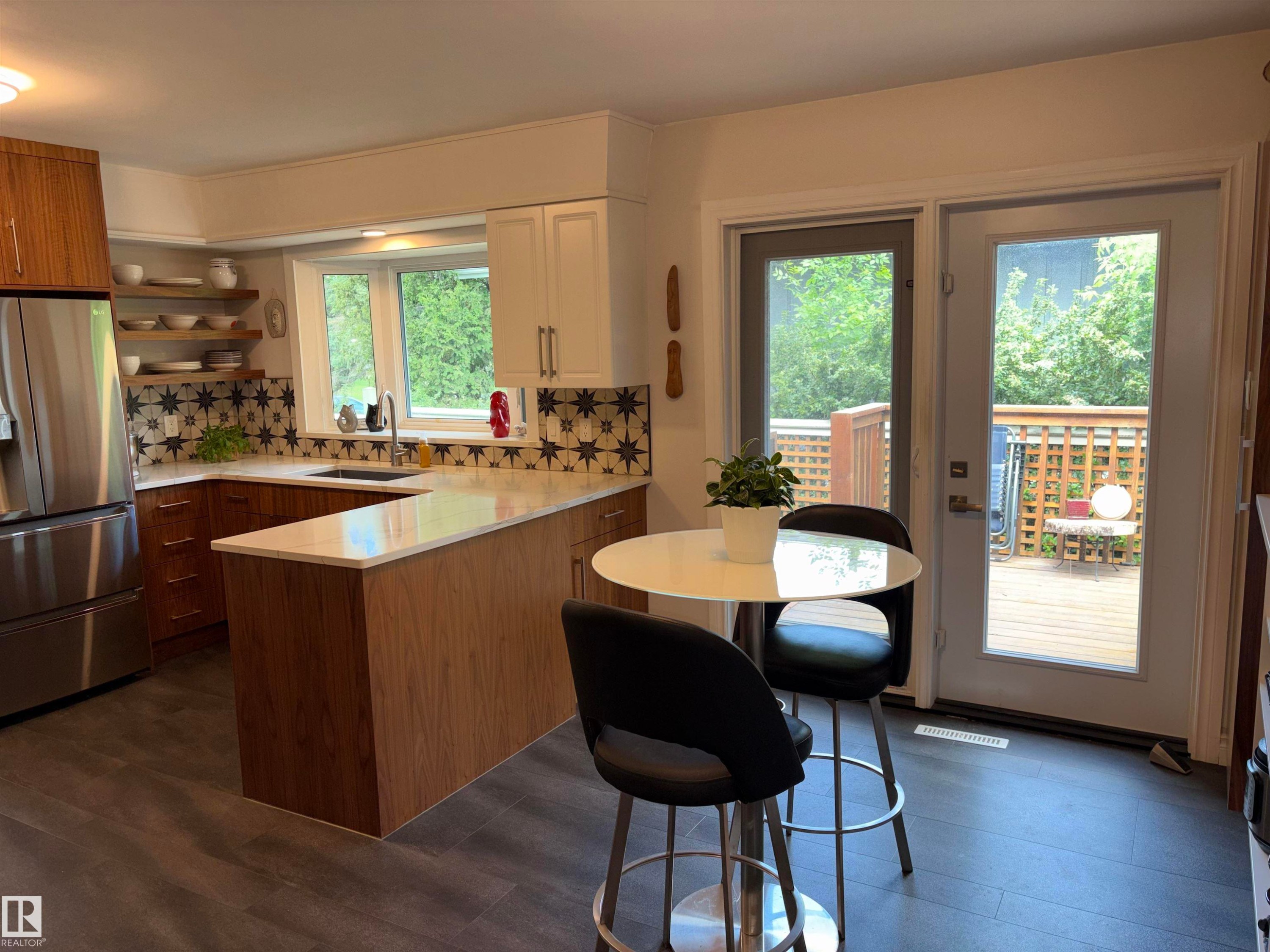 Contemporary kitchen featuring a bay window, two-tone cabinetry, patterned tile backsplash, and light countertops - 14016 85 Avenue Nw, Edmonton, AB - Indoor Photo Showing Kitchen