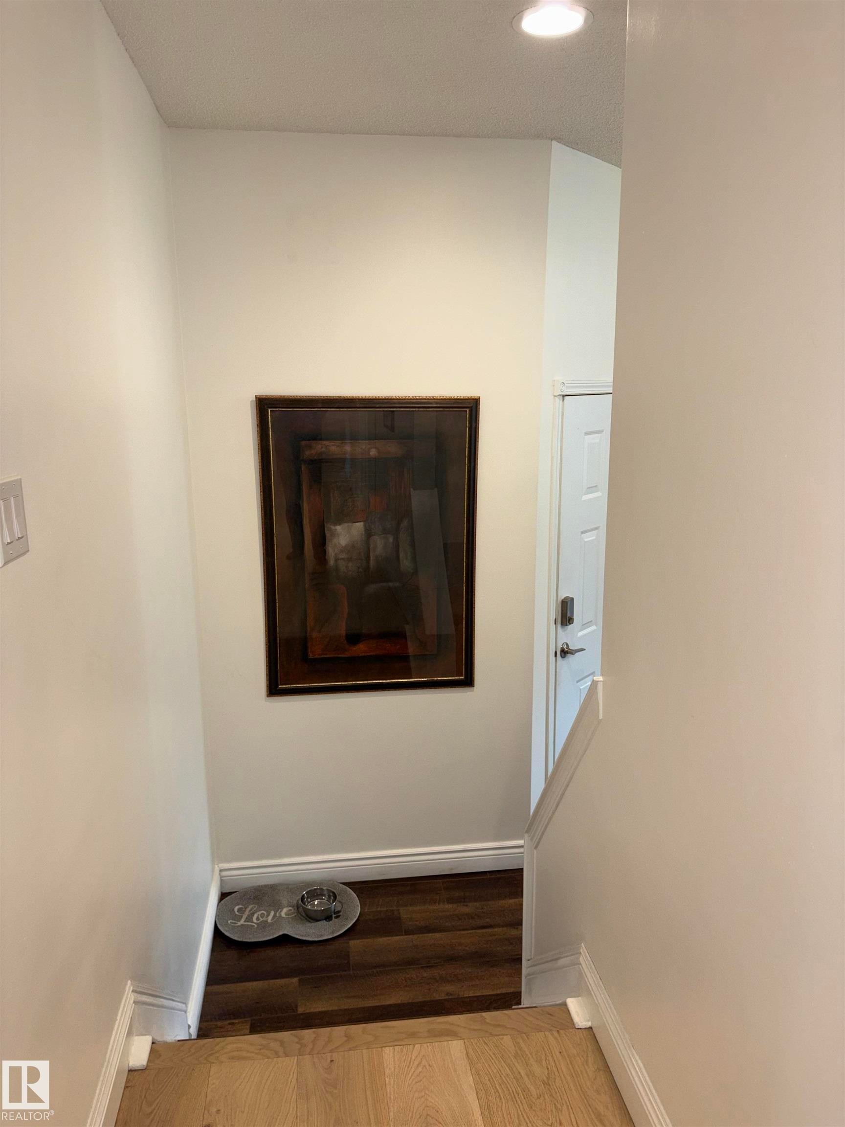 Split-level entry featuring wood-finish flooring, white baseboards, and overhead recessed lighting - 14016 85 Avenue Nw, Edmonton, AB - Indoor Photo Showing Other Room