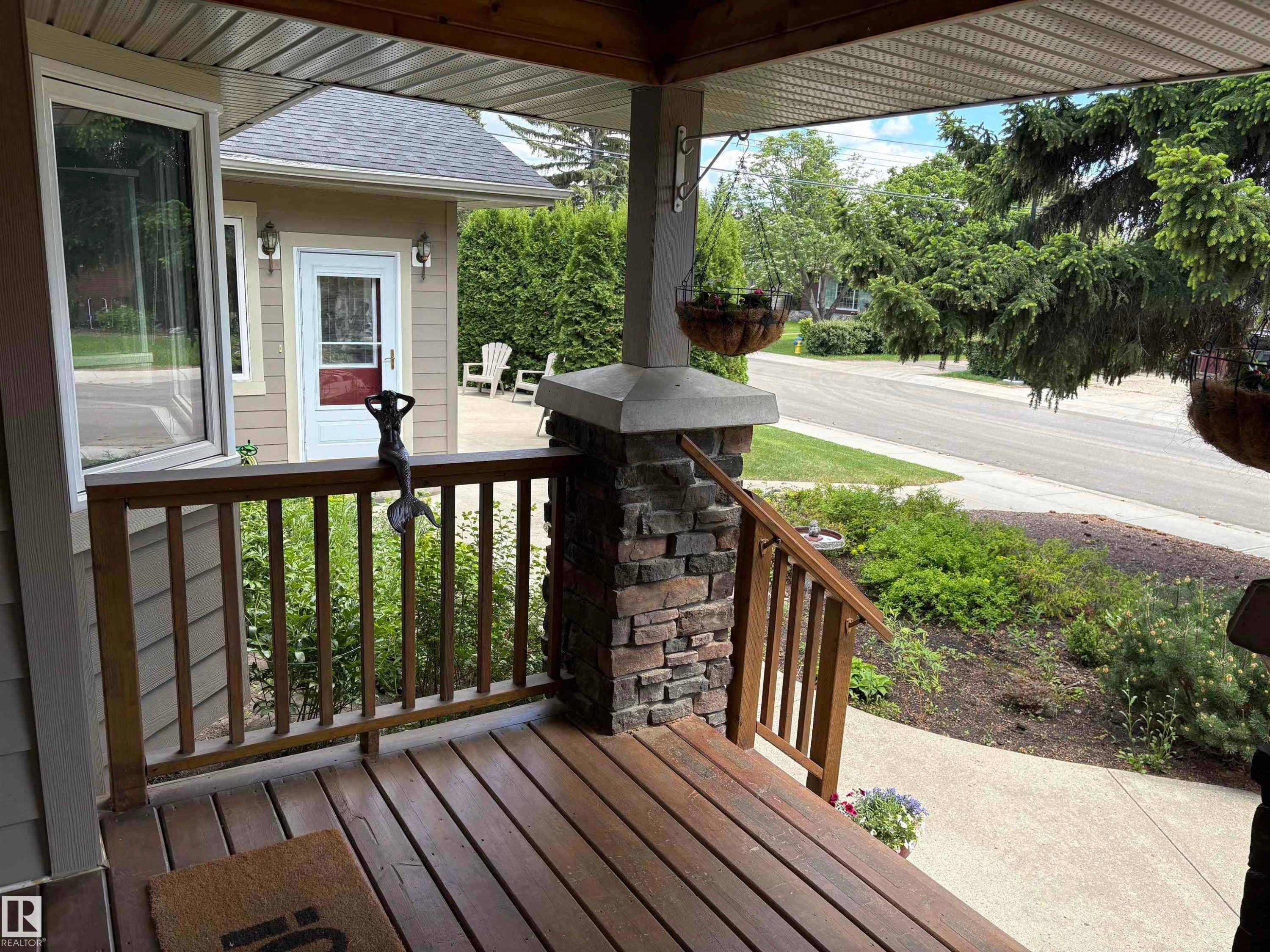 Inviting covered front porch with wood-finish decking, stone-clad pillar, and wood railing - 14016 85 Avenue Nw, Edmonton, AB - Outdoor With Deck Patio Veranda With Exterior