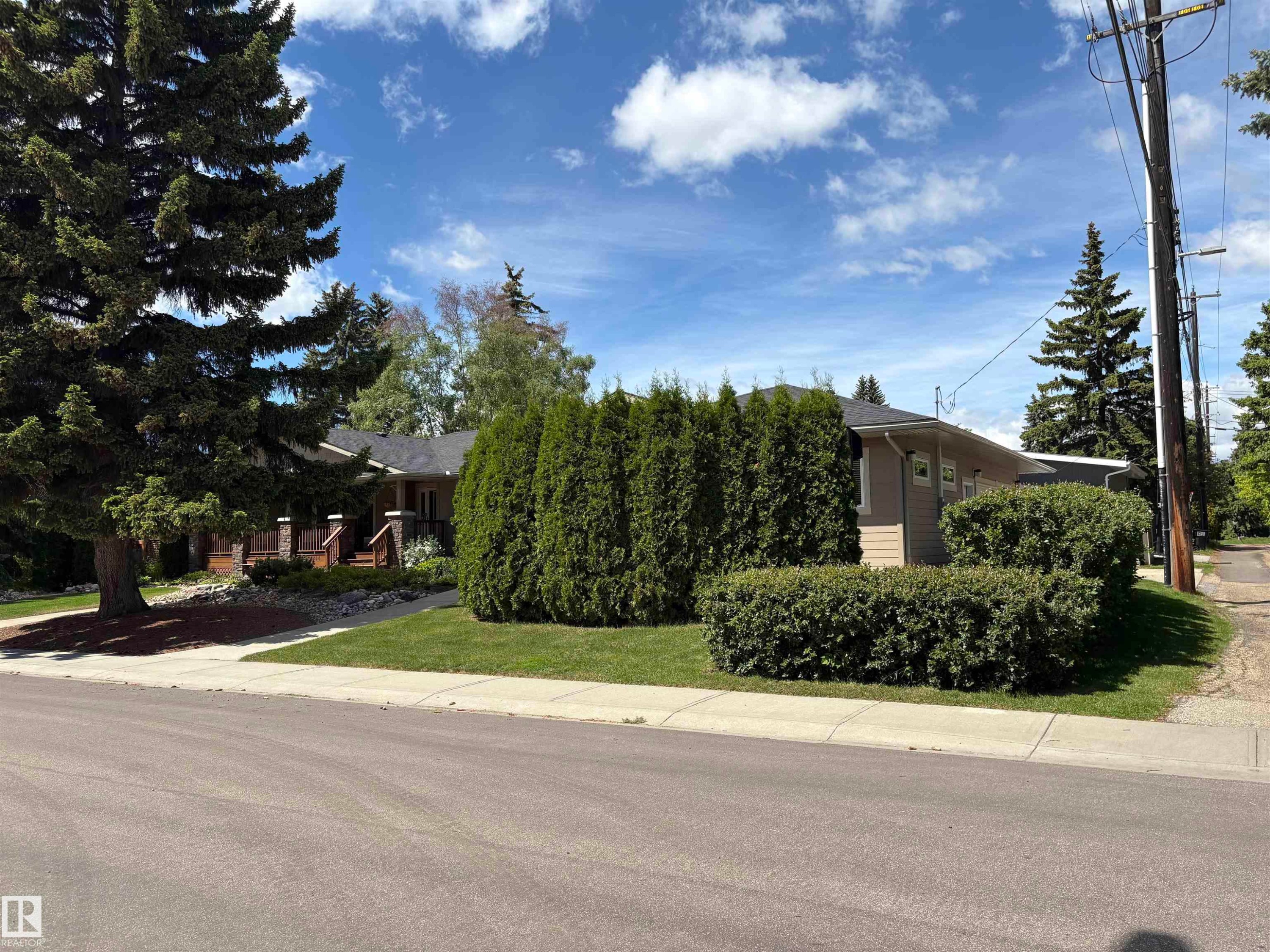 Ranch-style exterior with beige siding, a dark roof, and a covered front porch featuring stone accents - 14016 85 Avenue Nw, Edmonton, AB - Outdoor