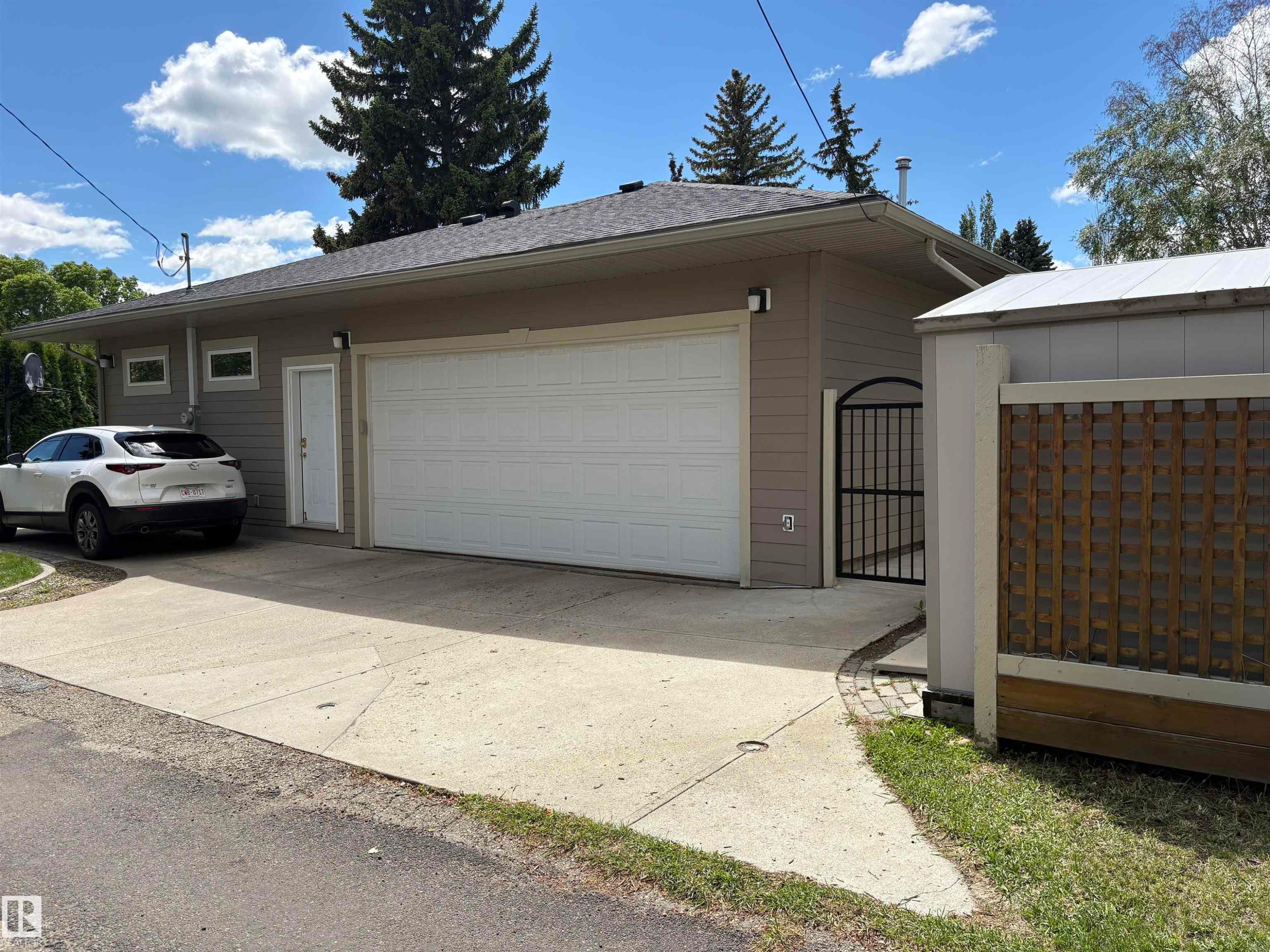 Attached two-car garage with a white sectional door, side entry door, and concrete driveway - 14016 85 Avenue Nw, Edmonton, AB - Outdoor With Exterior
