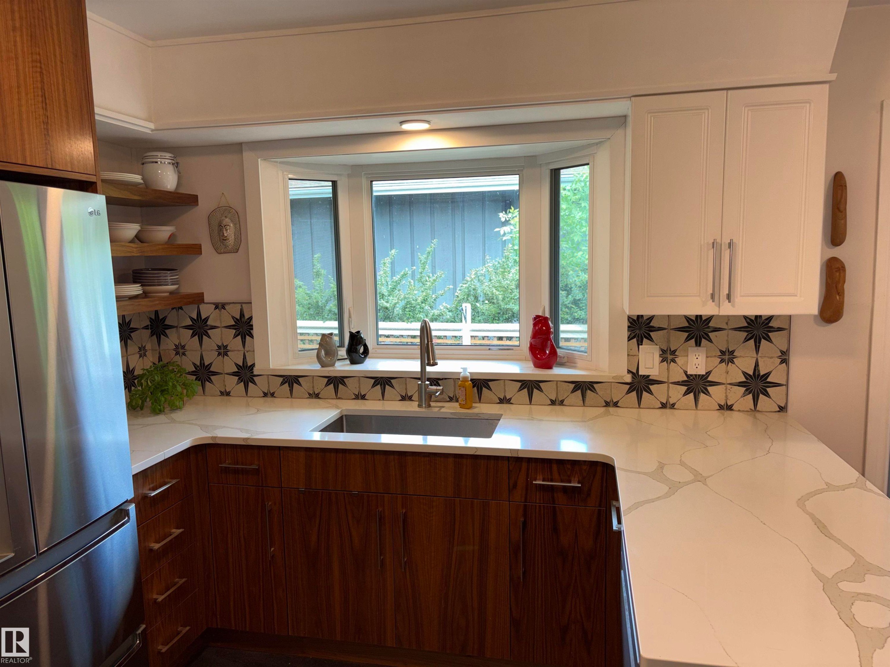 Kitchen featuring a bay window, white countertops with veining, wood-finish lower cabinetry, white upper cabinetry, and patterned tile backsplash - 14016 85 Avenue Nw, Edmonton, AB - Indoor Photo Showing Kitchen