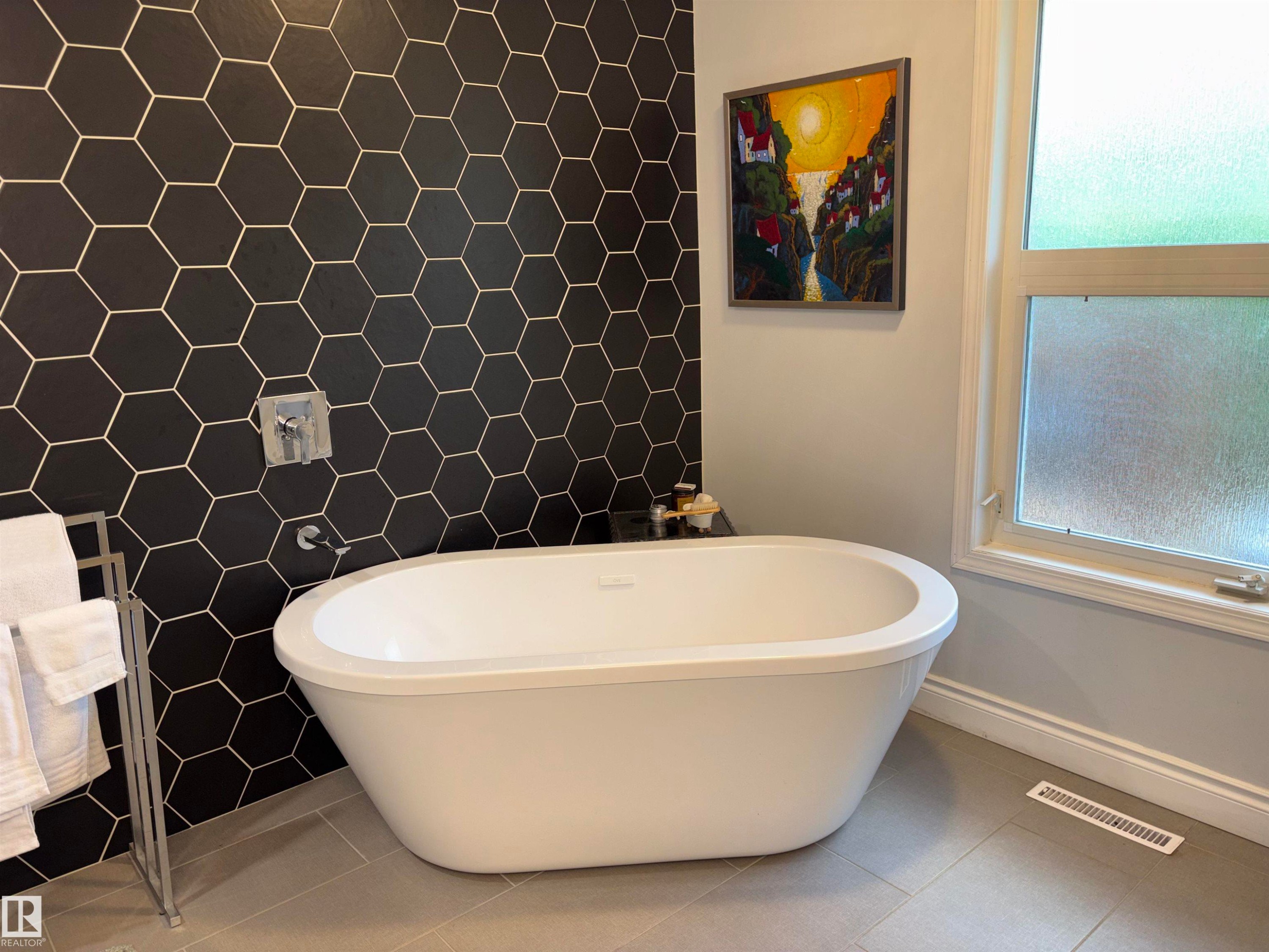 Freestanding soaking tub against a black hexagonal tile accent wall - 14016 85 Avenue Nw, Edmonton, AB - Indoor Photo Showing Bathroom