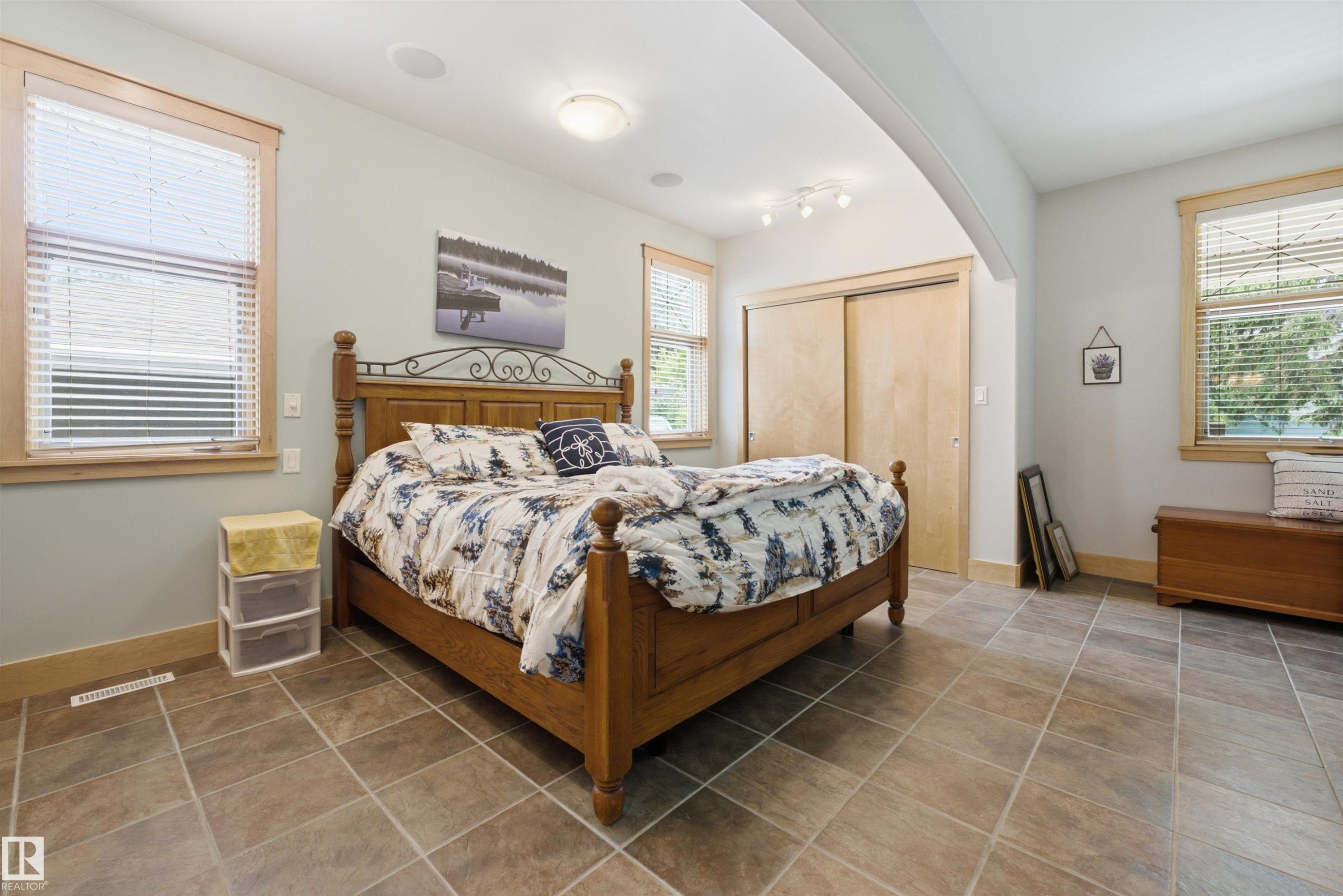 Spacious room featuring tile flooring, light-toned walls, and multiple windows with wood trim - A38 Bernice Ave, Rural Leduc County, AB