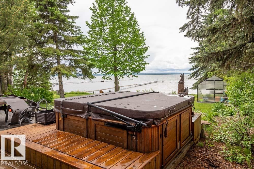 Outdoor spa deck featuring a spa with a hard cover, wood-finish siding, and a multi-level wood-finish deck - A38 Bernice Ave, Rural Leduc County, AB