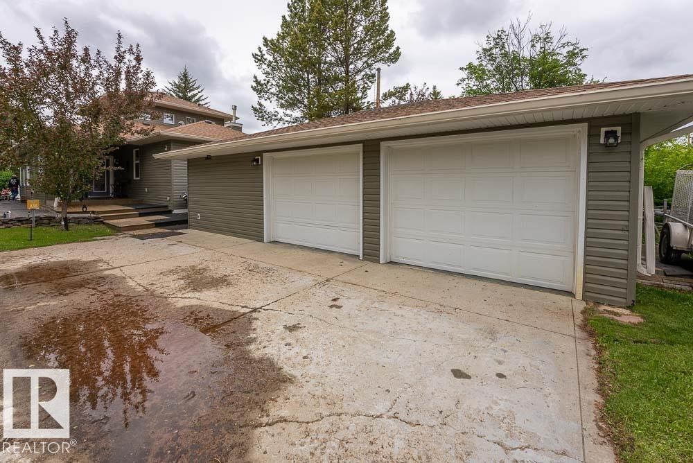 Attached two-car garage with white paneled doors and an exterior light fixture - A38 Bernice Ave, Rural Leduc County, AB
