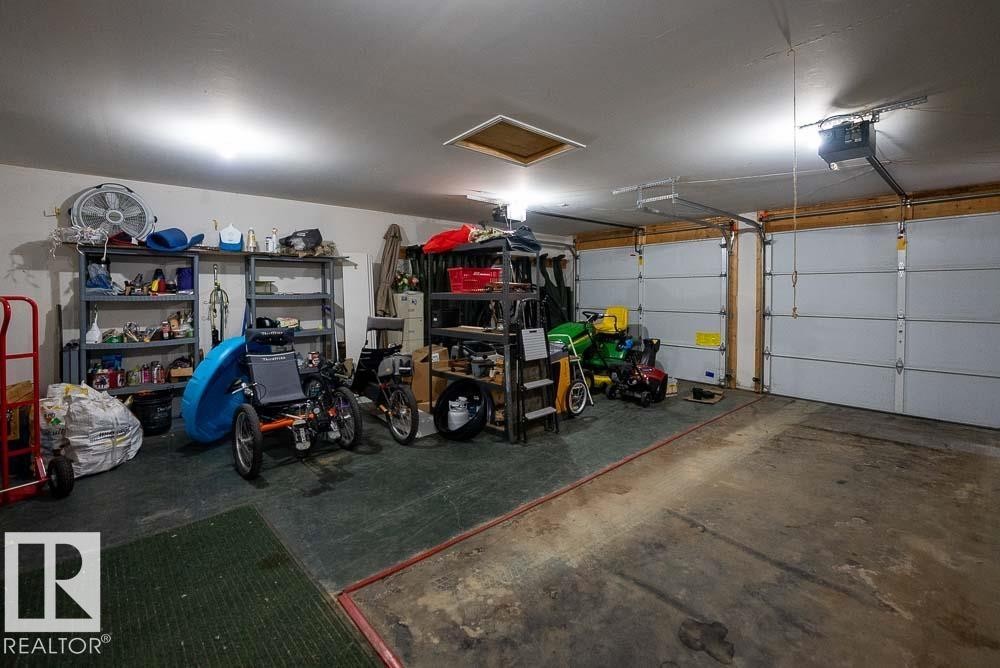 Two-car garage featuring a concrete floor, overhead lighting, and automatic garage door openers - A38 Bernice Ave, Rural Leduc County, AB