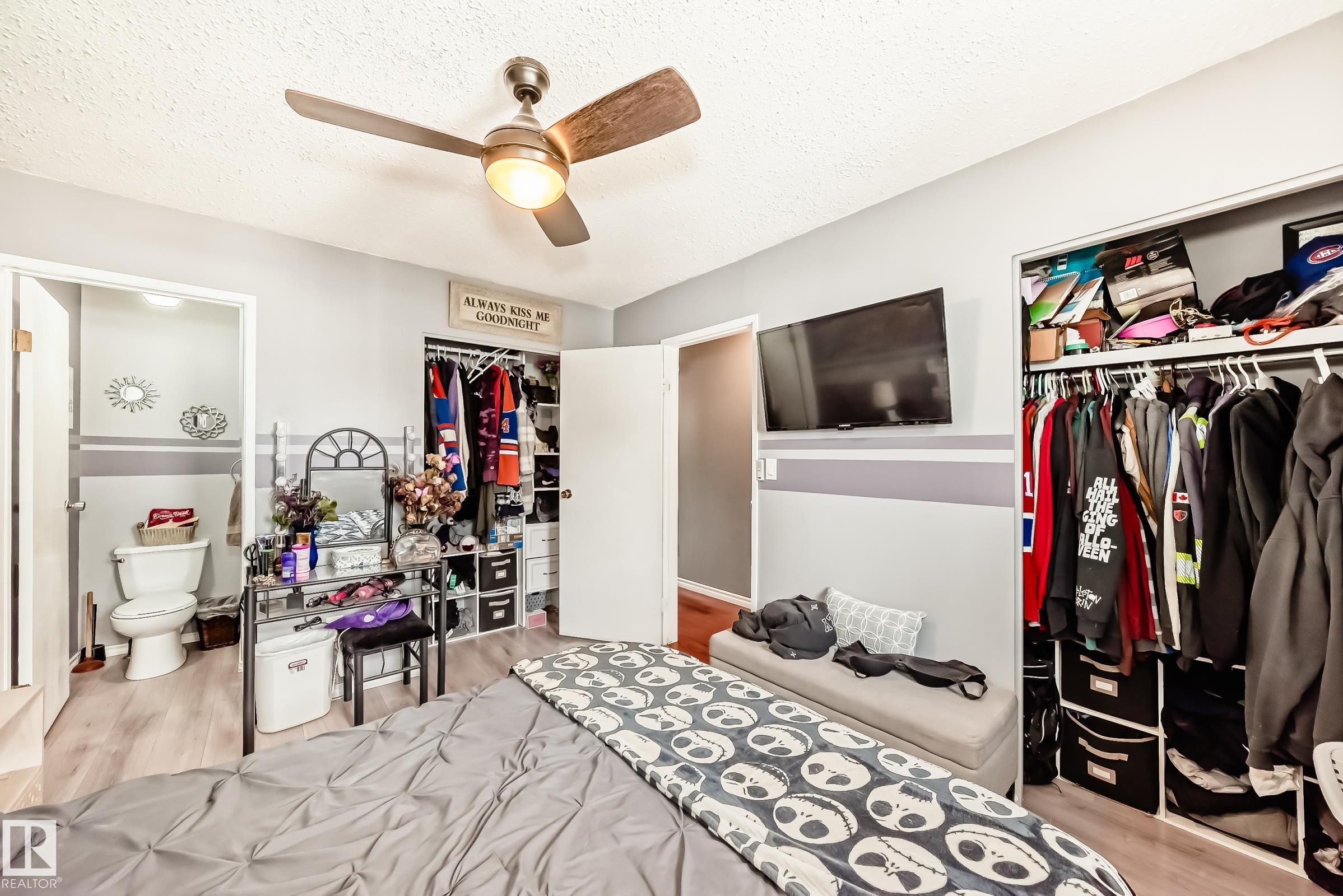Room featuring light gray walls, wood-finish flooring, a ceiling fan with integrated lighting, and a closet with bifold doors - 5106 19 Avenue, Edmonton, AB