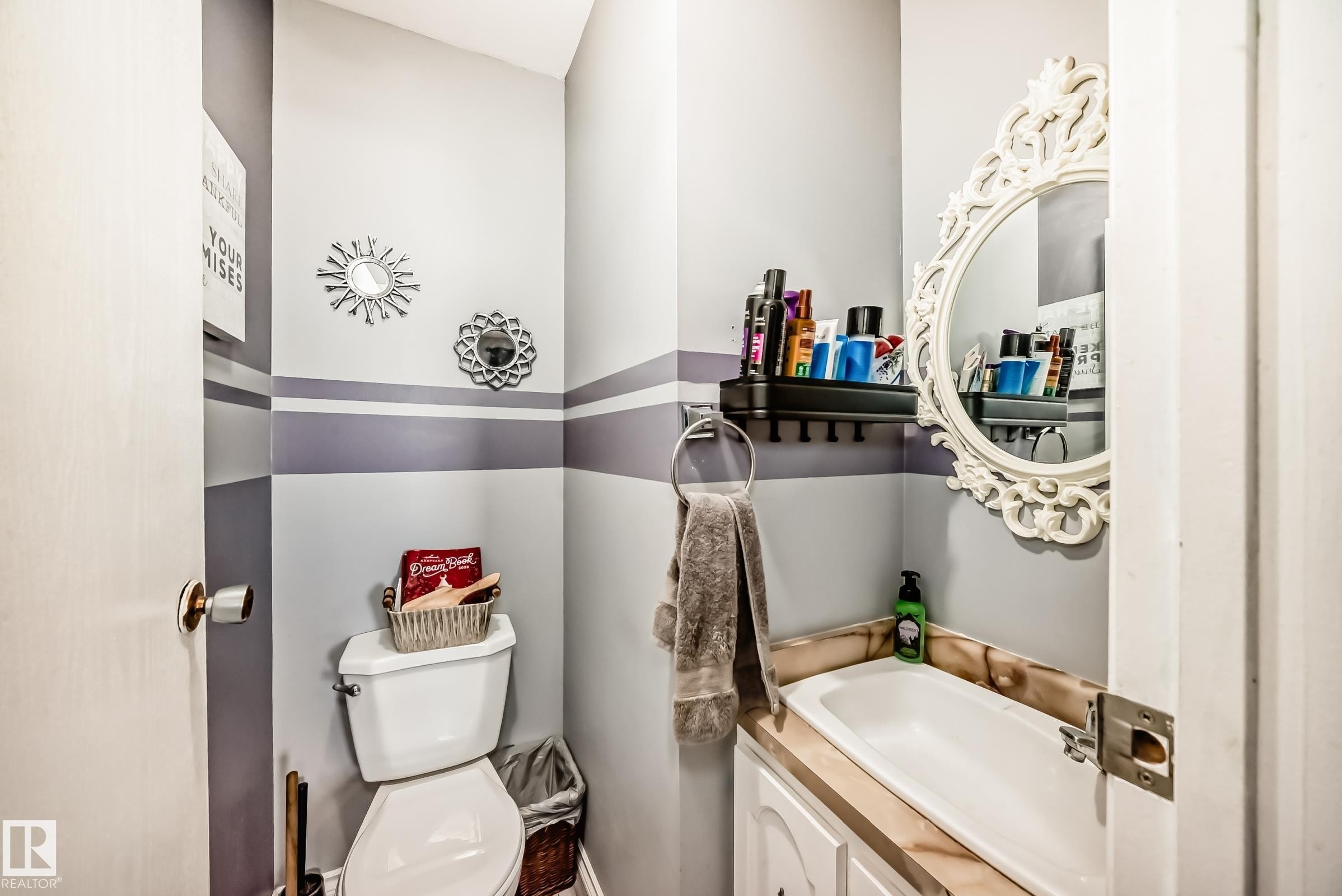 Compact bathroom featuring a white toilet, integrated sink with a light-toned countertop, and a white vanity cabinet - 5106 19 Avenue, Edmonton, AB
