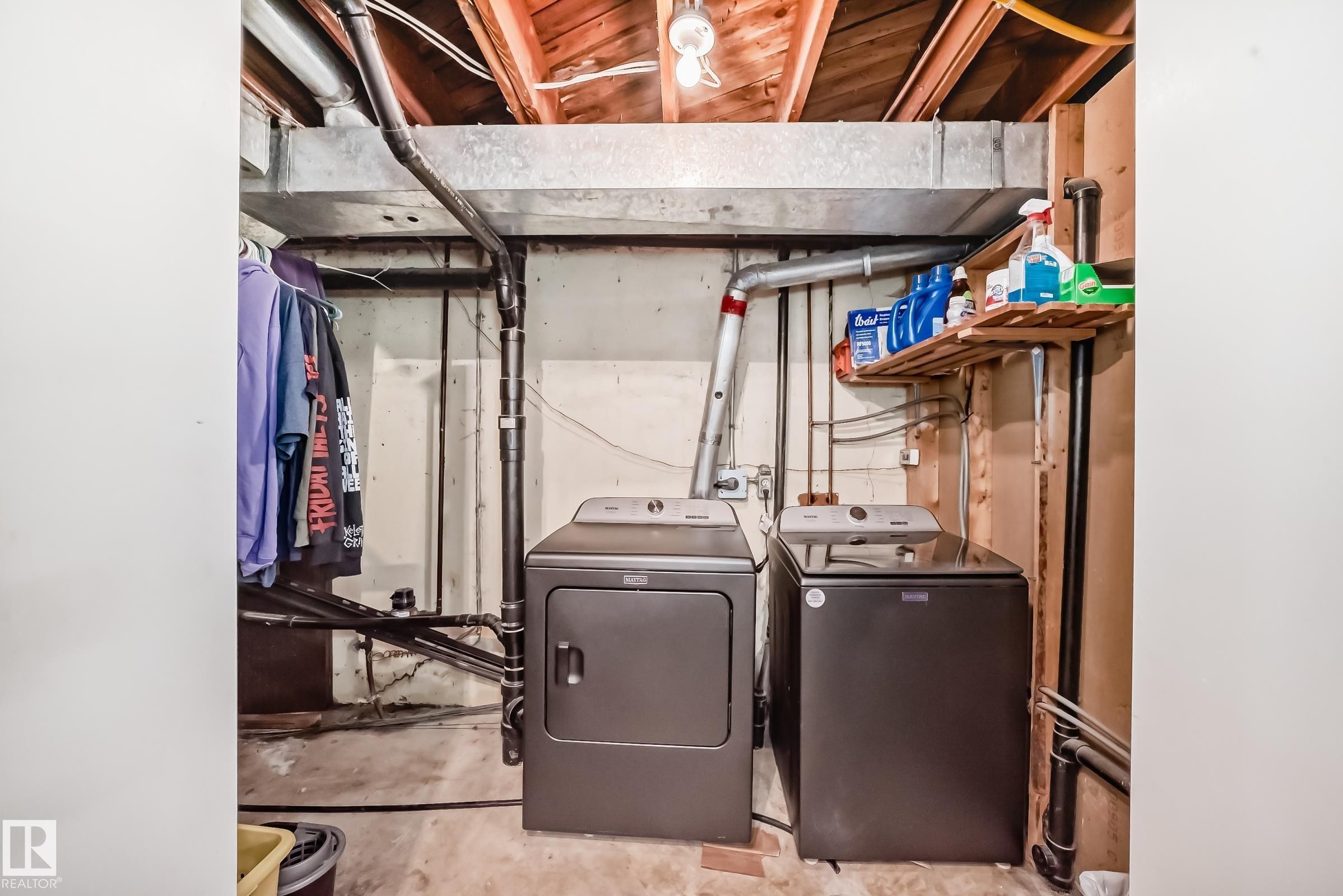 Dedicated laundry area featuring a washer and dryer set, exposed wood ceiling joists, and a metal HVAC duct - 5106 19 Avenue, Edmonton, AB