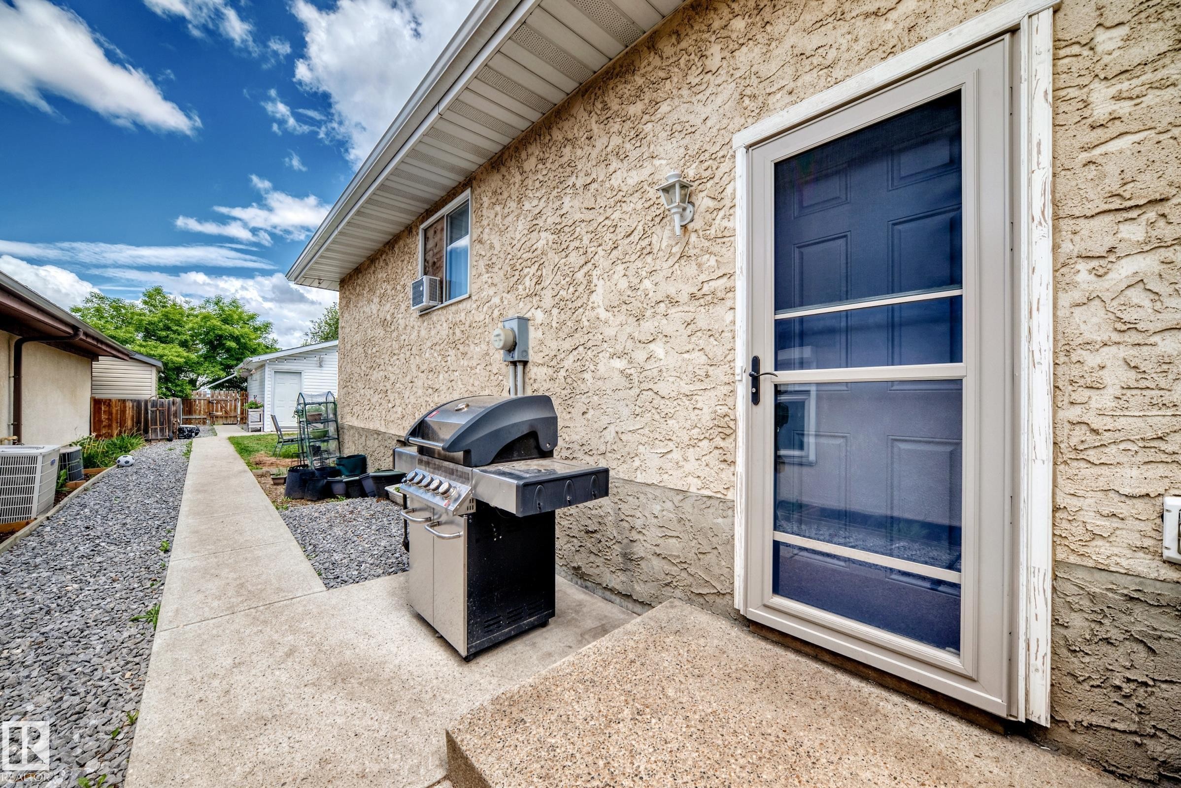 Rear exterior with stucco siding and a concrete patio - 5106 19 Avenue, Edmonton, AB