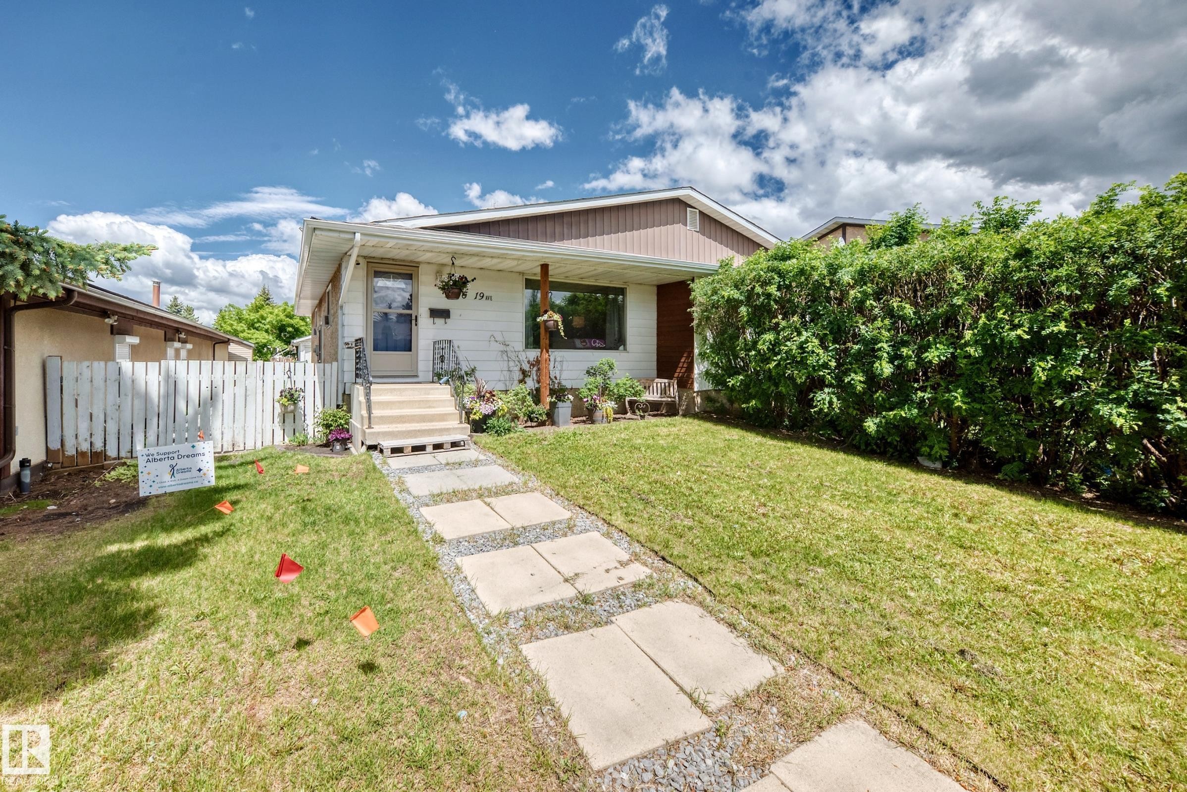 Single-story residence featuring a covered front porch with supporting columns and a partially enclosed white picket fence - 5106 19 Avenue, Edmonton, AB