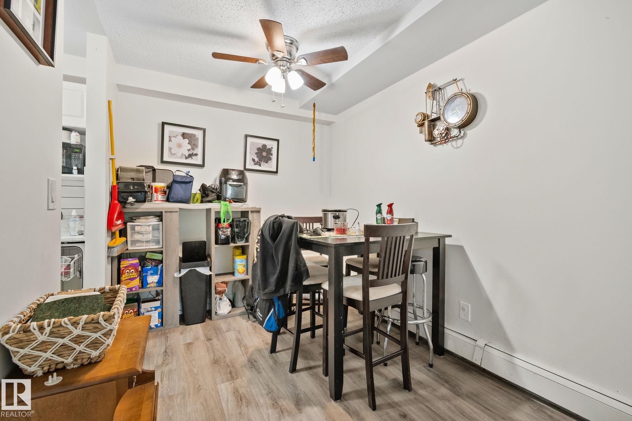 Dining area featuring wood-finish flooring, a ceiling fan with light fixture, and a built-in baseboard heater - 115 4608 52 Avenue, Stony Plain, AB