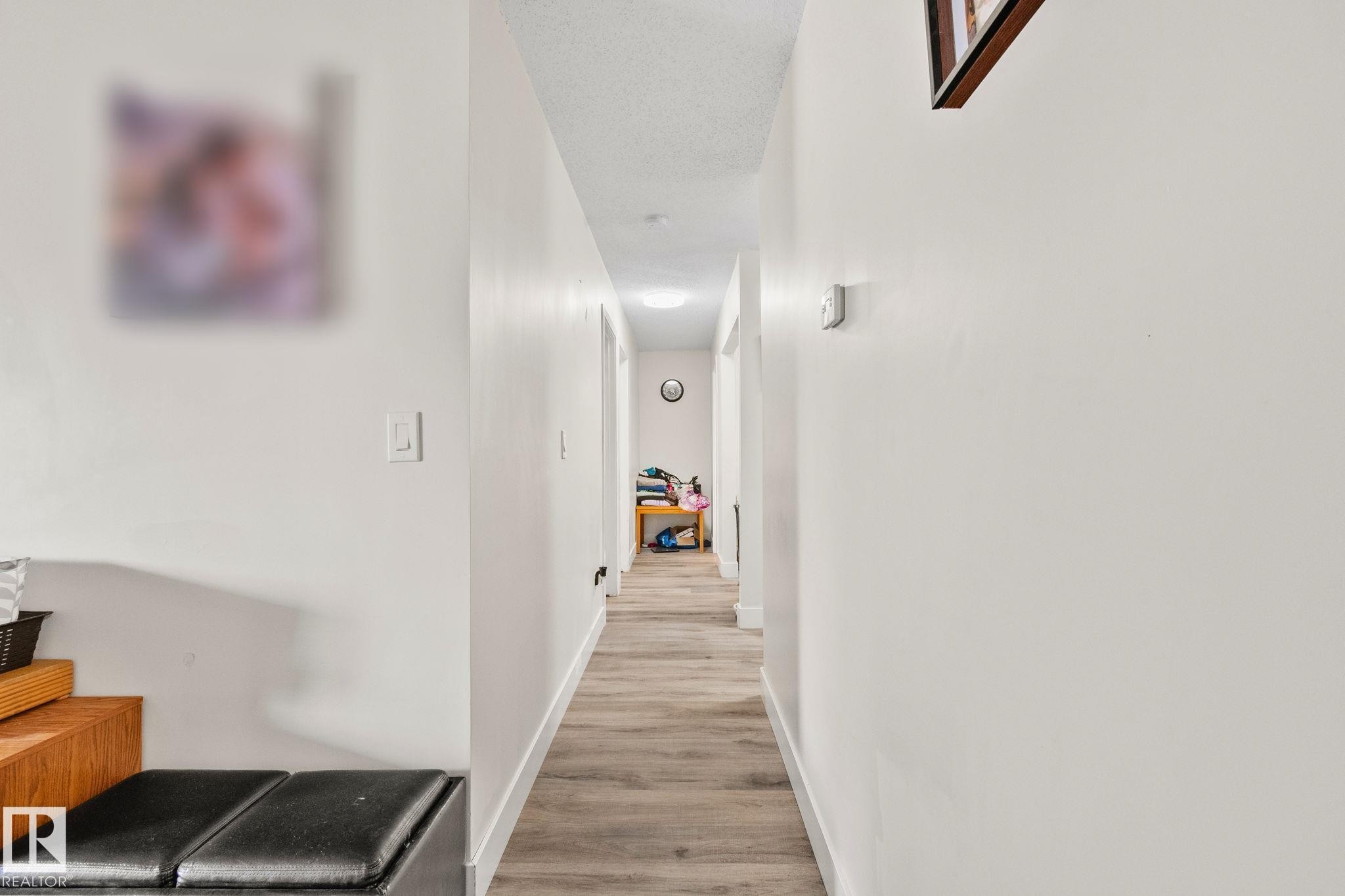 Long hallway featuring wood-finish flooring, white painted walls, and recessed lighting - 115 4608 52 Avenue, Stony Plain, AB