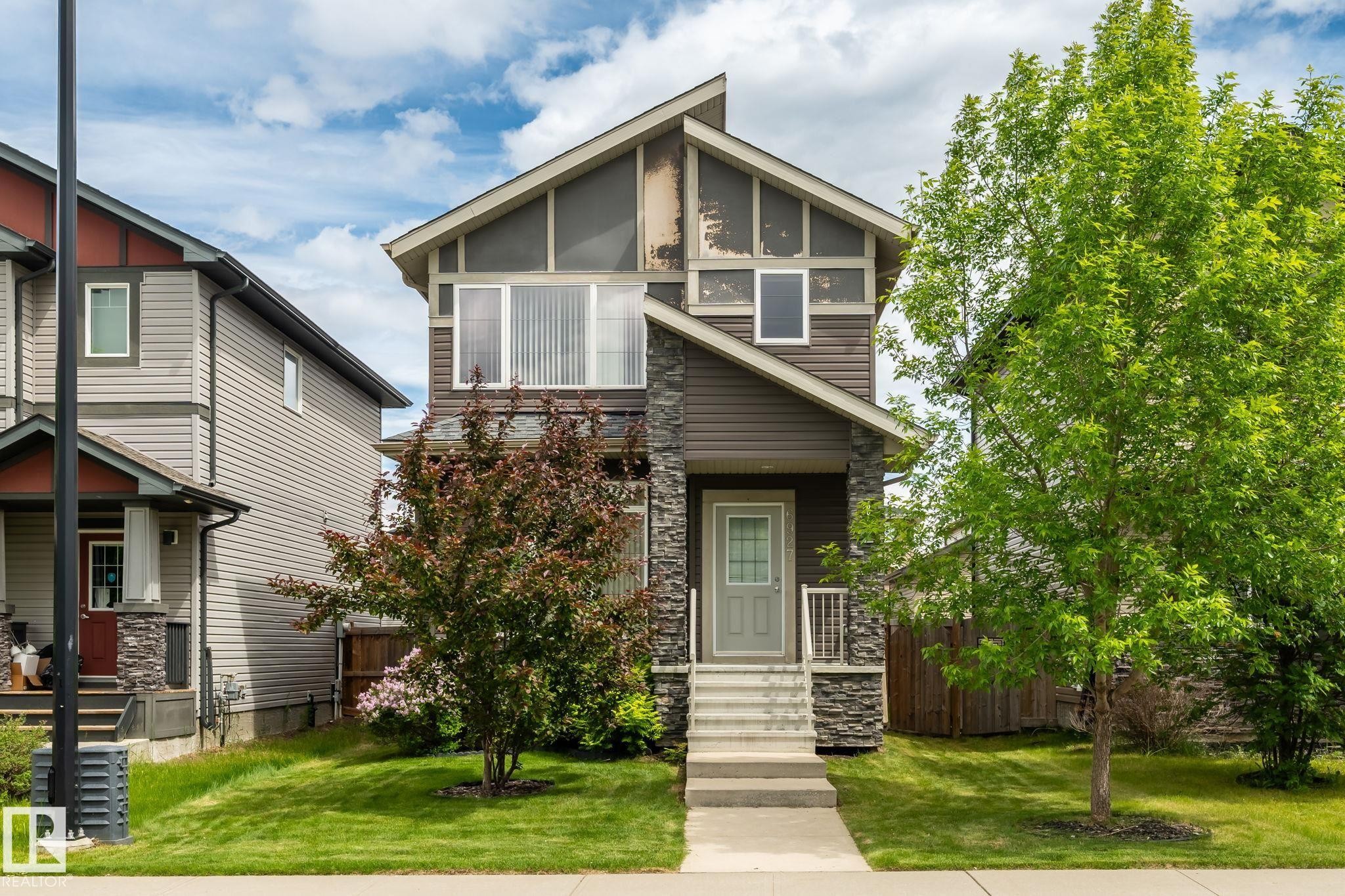 Contemporary home featuring a stone facade and dark siding accents - 6927 Cardinal Wynd Sw, Edmonton, AB - Outdoor