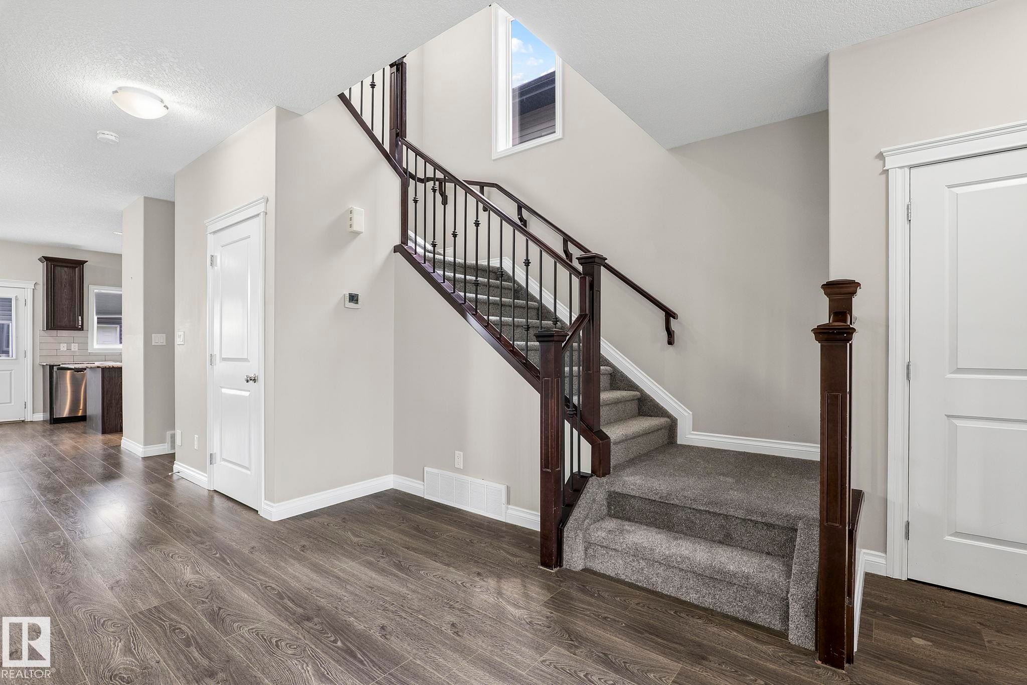 Staircase featuring dark wood newel posts and handrails with black metal balusters - 6927 Cardinal Wynd Sw, Edmonton, AB - Indoor Photo Showing Other Room