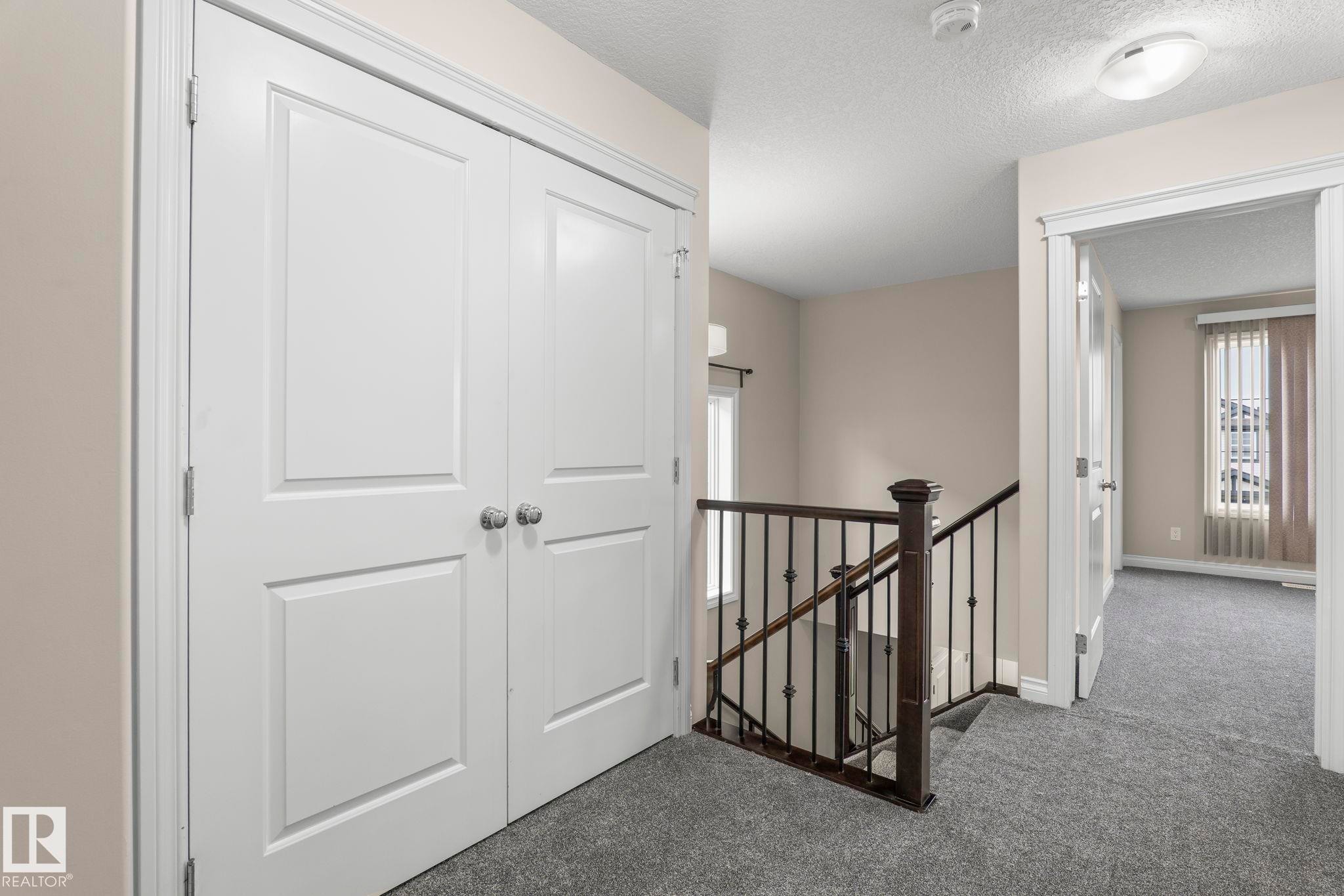 Hallway featuring white panel doors, neutral wall paint, and grey carpeting - 6927 Cardinal Wynd Sw, Edmonton, AB - Indoor Photo Showing Other Room