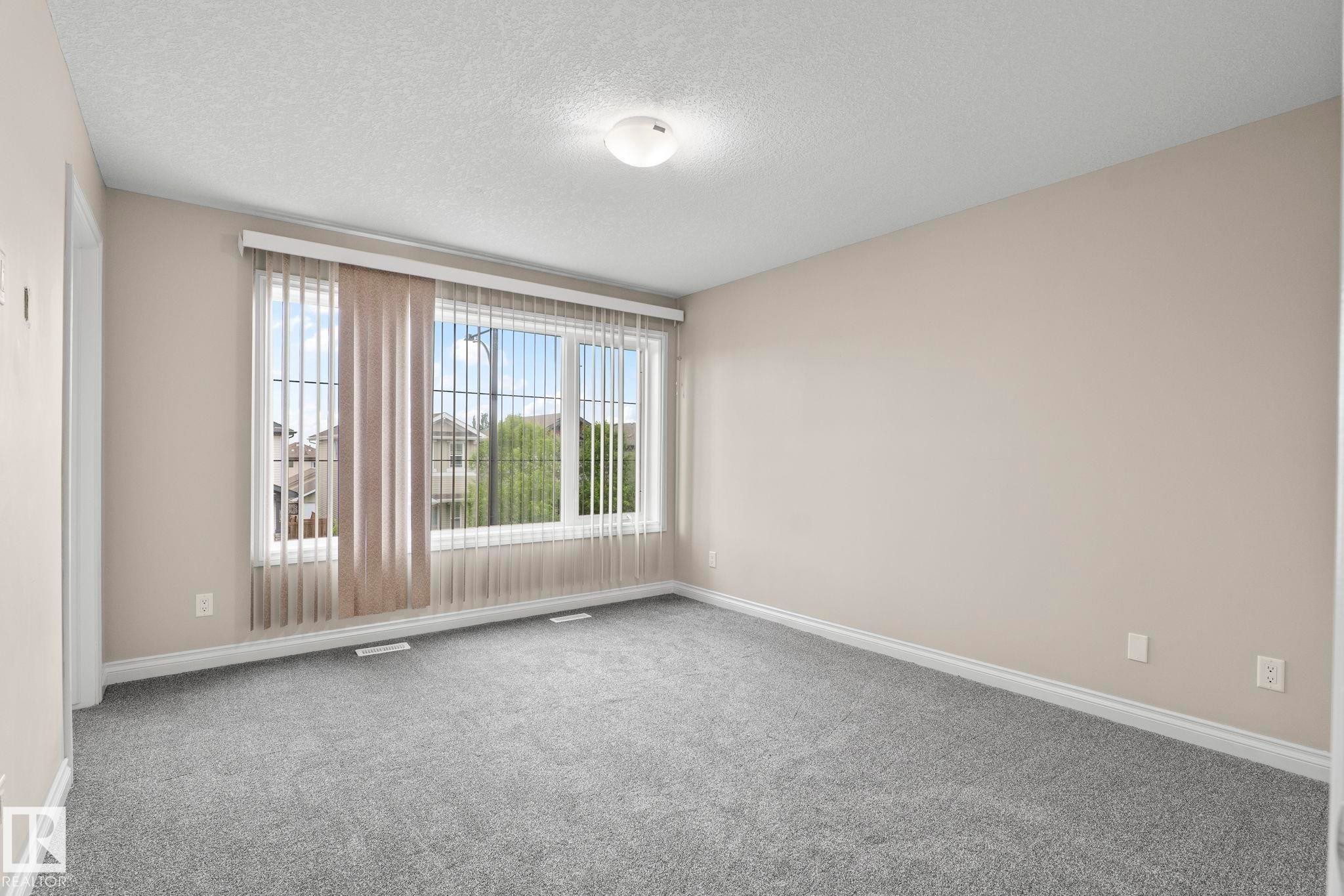 Spacious room featuring neutral carpeting, light-toned wall paint, and white trim - 6927 Cardinal Wynd Sw, Edmonton, AB - Indoor Photo Showing Other Room