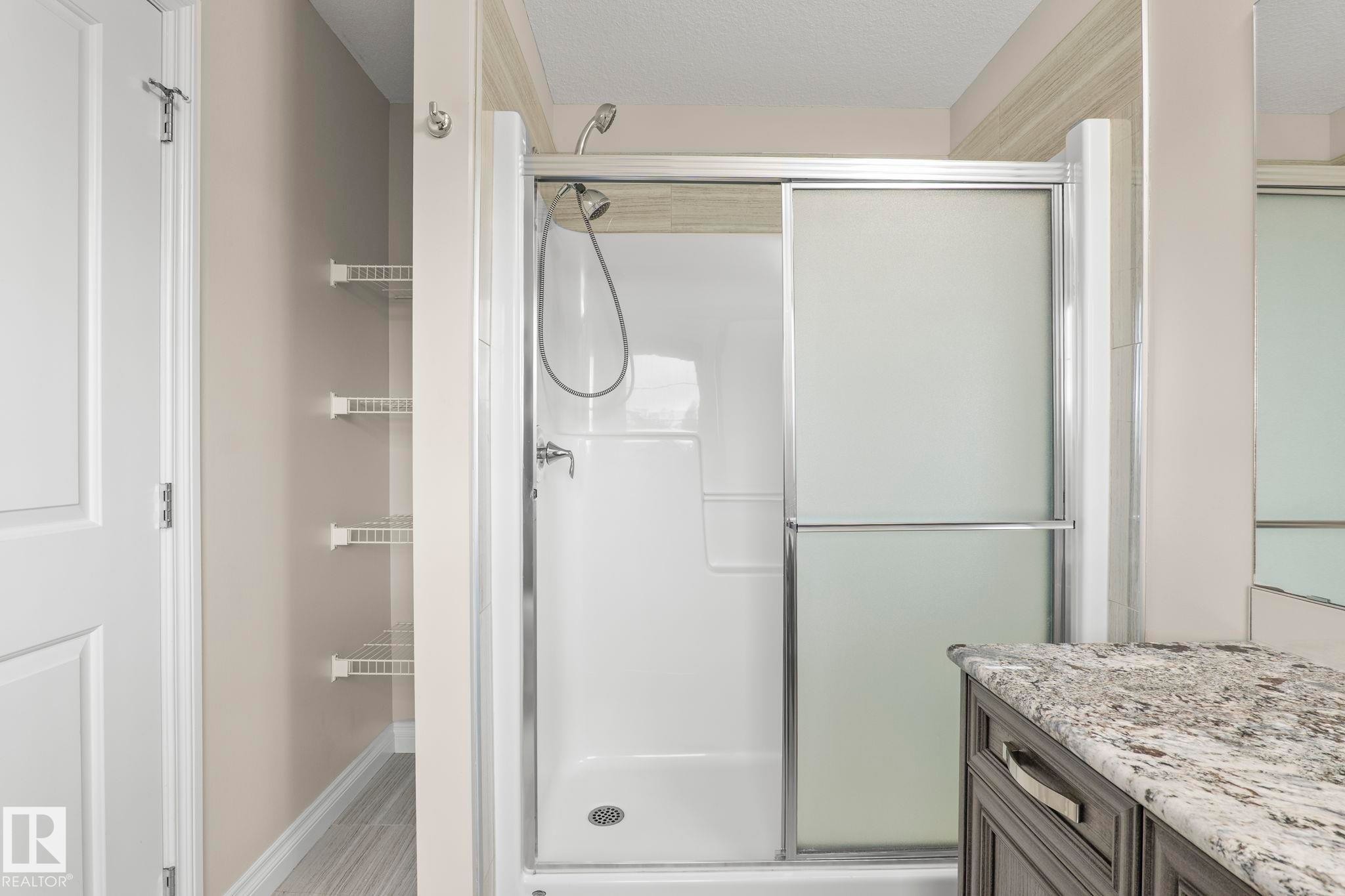 Shower with sliding frosted glass doors, chrome fixtures, and white acrylic surround - 6927 Cardinal Wynd Sw, Edmonton, AB - Indoor Photo Showing Bathroom