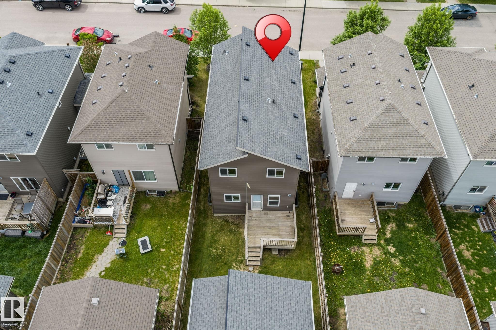 Rear elevation featuring a private fenced yard, wood deck, and upper-level windows - 6927 Cardinal Wynd Sw, Edmonton, AB - Outdoor