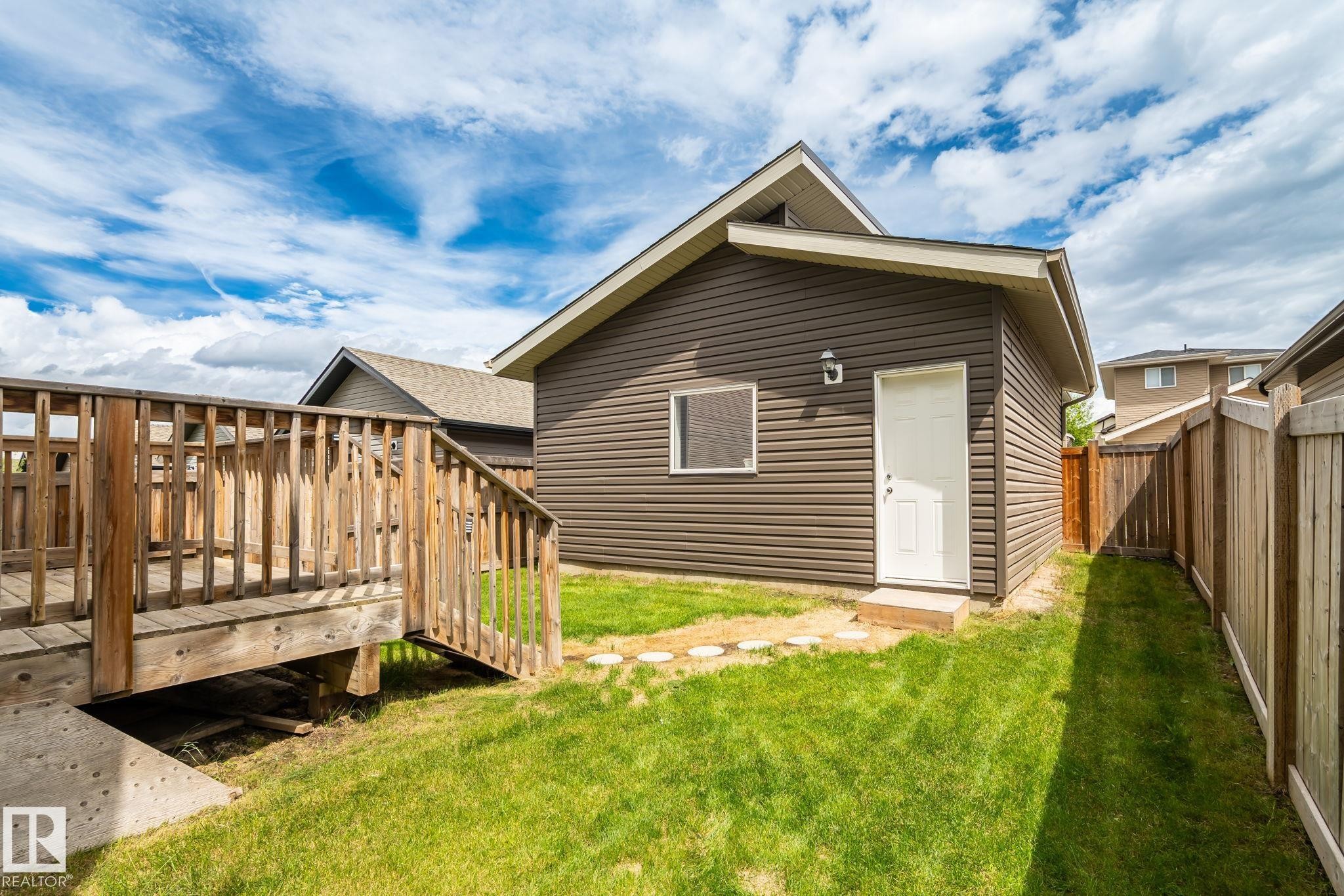 Expansive green lawn with a wood deck and privacy fencing - 6927 Cardinal Wynd Sw, Edmonton, AB - Outdoor