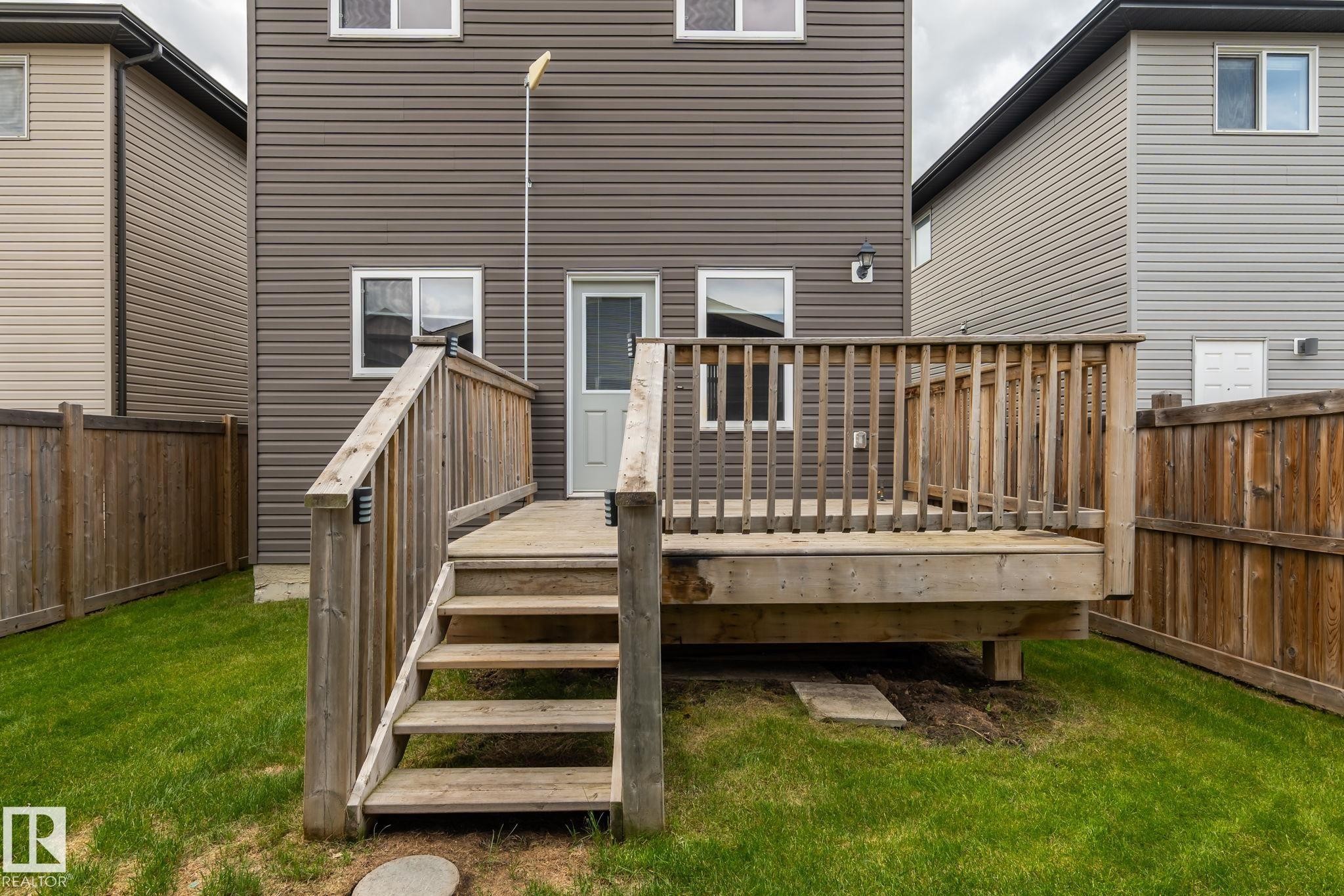 Rear exterior featuring a wood deck with stairs, horizontal siding, and multiple windows - 6927 Cardinal Wynd Sw, Edmonton, AB - Outdoor With Deck Patio Veranda With Exterior
