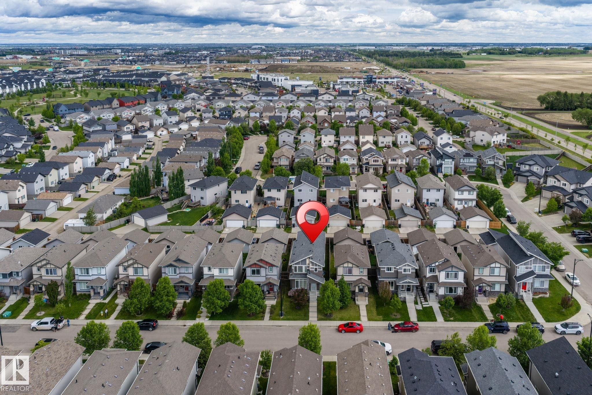 Residential property featuring a light-toned exterior, dark roof, and an attached front garage - 6927 Cardinal Wynd Sw, Edmonton, AB - Outdoor With View