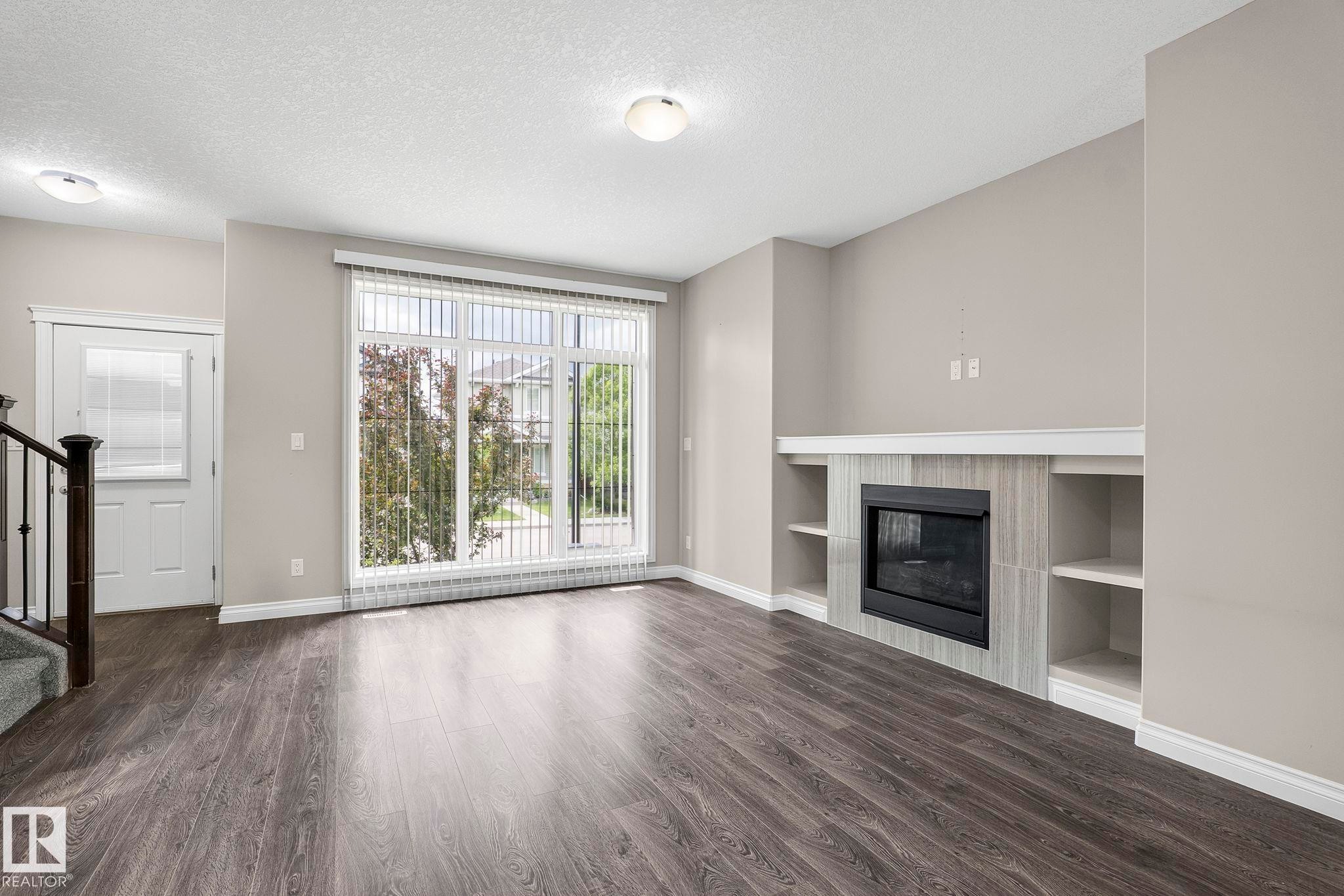 Open-concept living space with dark wood-finish flooring - 6927 Cardinal Wynd Sw, Edmonton, AB - Indoor Photo Showing Living Room With Fireplace