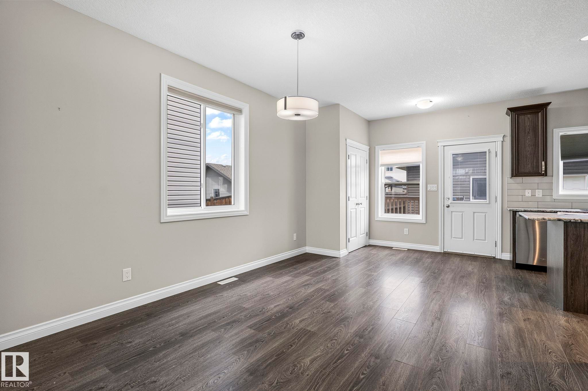 Spacious room with dark wood-finish flooring, light grey walls, and white trim - 6927 Cardinal Wynd Sw, Edmonton, AB - Indoor Photo Showing Kitchen
