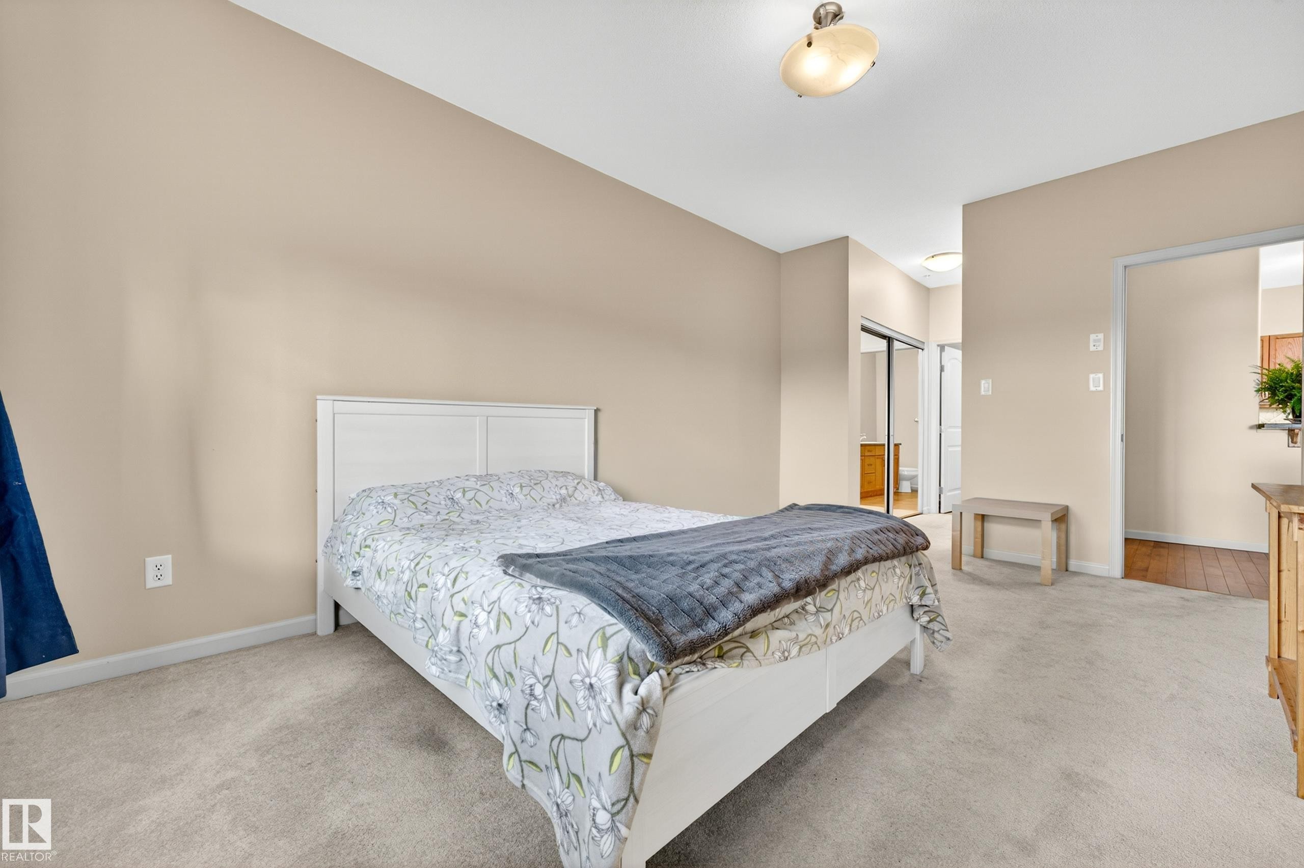 Carpeted room featuring neutral wall tones, a ceiling-mounted light fixture, and a built-in closet with sliding mirrored doors - 133 2503 Hanna Crescent, Edmonton, AB