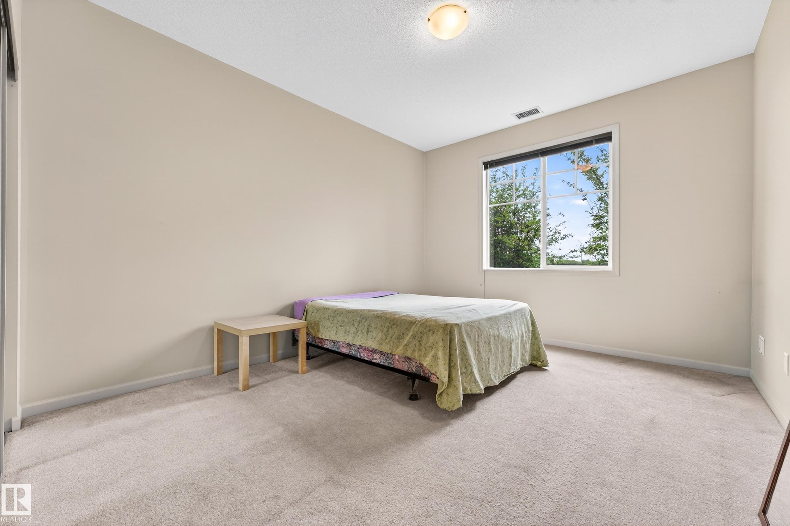 Room featuring neutral wall tones, light-colored carpeting, a large window, and a flush-mount ceiling light fixture - 133 2503 Hanna Crescent, Edmonton, AB
