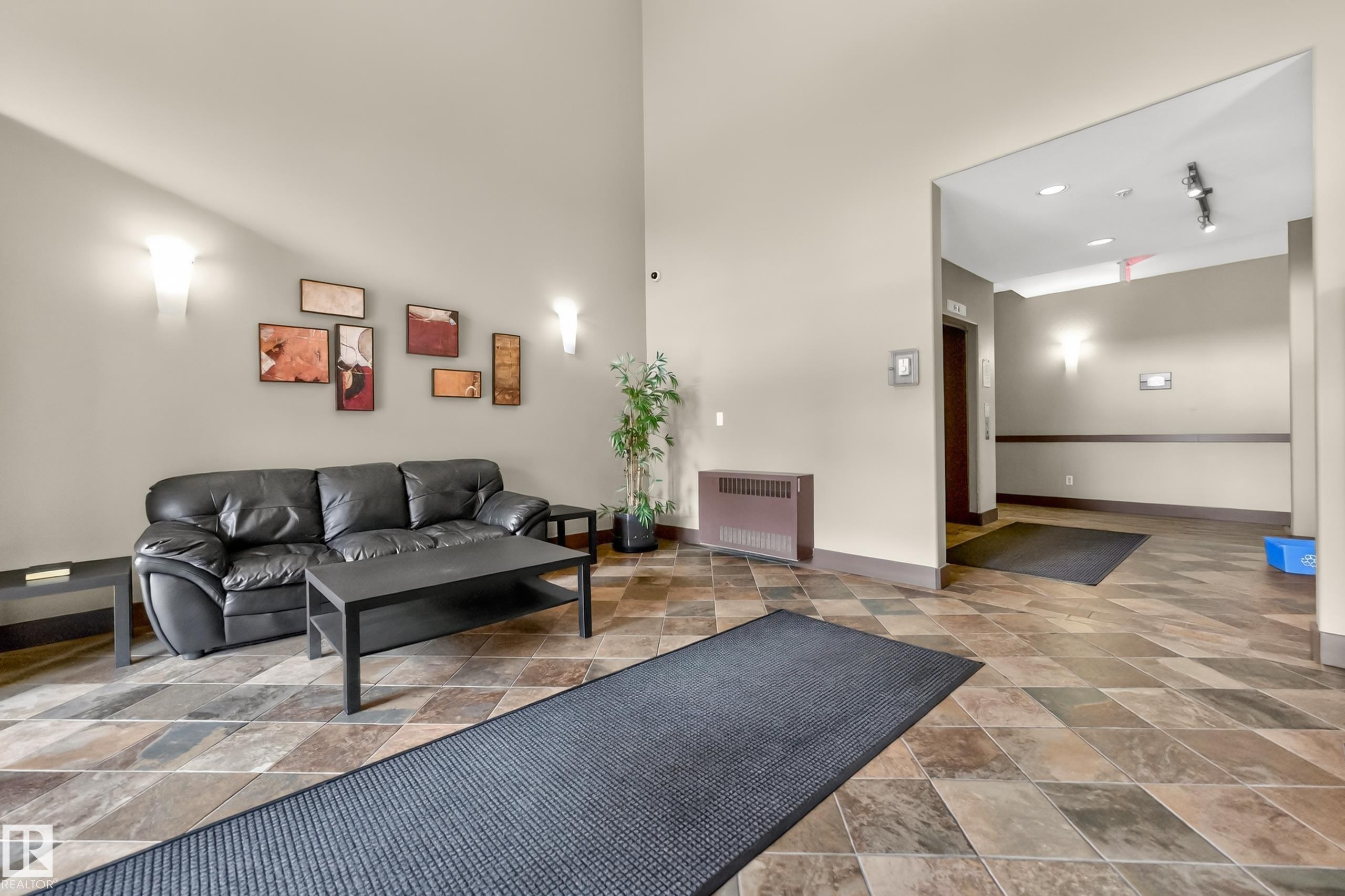 Lobby area featuring diamond-patterned floor tiling, wall sconces, and a high ceiling - 133 2503 Hanna Crescent, Edmonton, AB