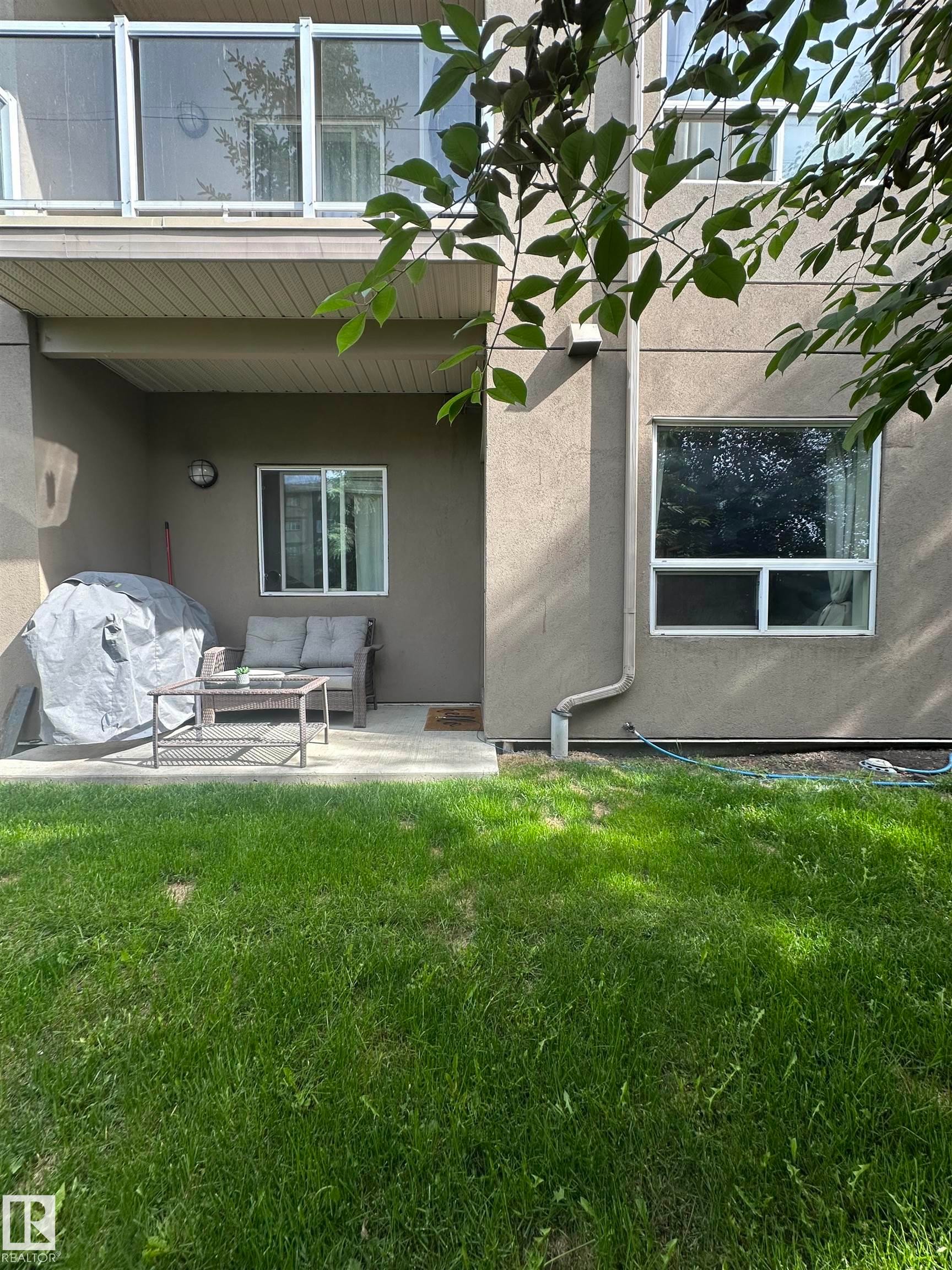 Multi-story residential building featuring a light-toned stucco exterior with contrasting dark shingled roofs - 116 5005 165 Avenue, Edmonton, AB