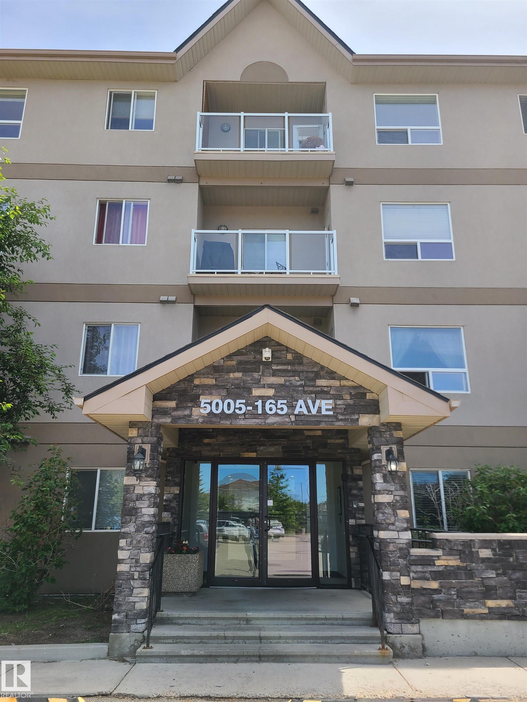 Multi-story building featuring a stone-clad entrance with glass double doors - 116 5005 165 Avenue, Edmonton, AB