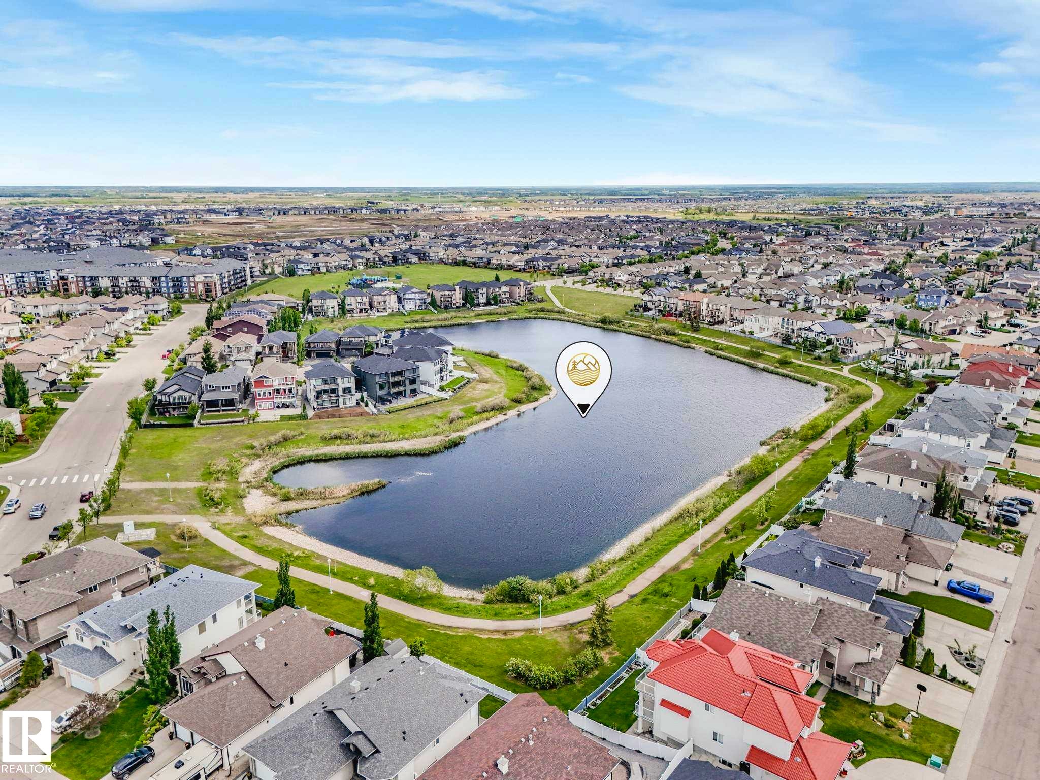 Aerial perspective showcasing a residential area with a prominent body of water and surrounding green spaces - 117 6070 Schonsee Way, Edmonton, AB