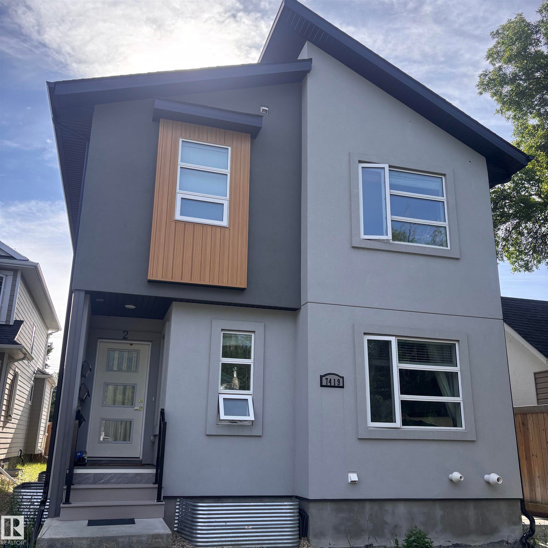Modern multi-story exterior featuring a light gray stucco finish and a contrasting dark gray facade - 7419 106 Street Nw, Edmonton, AB - Outdoor