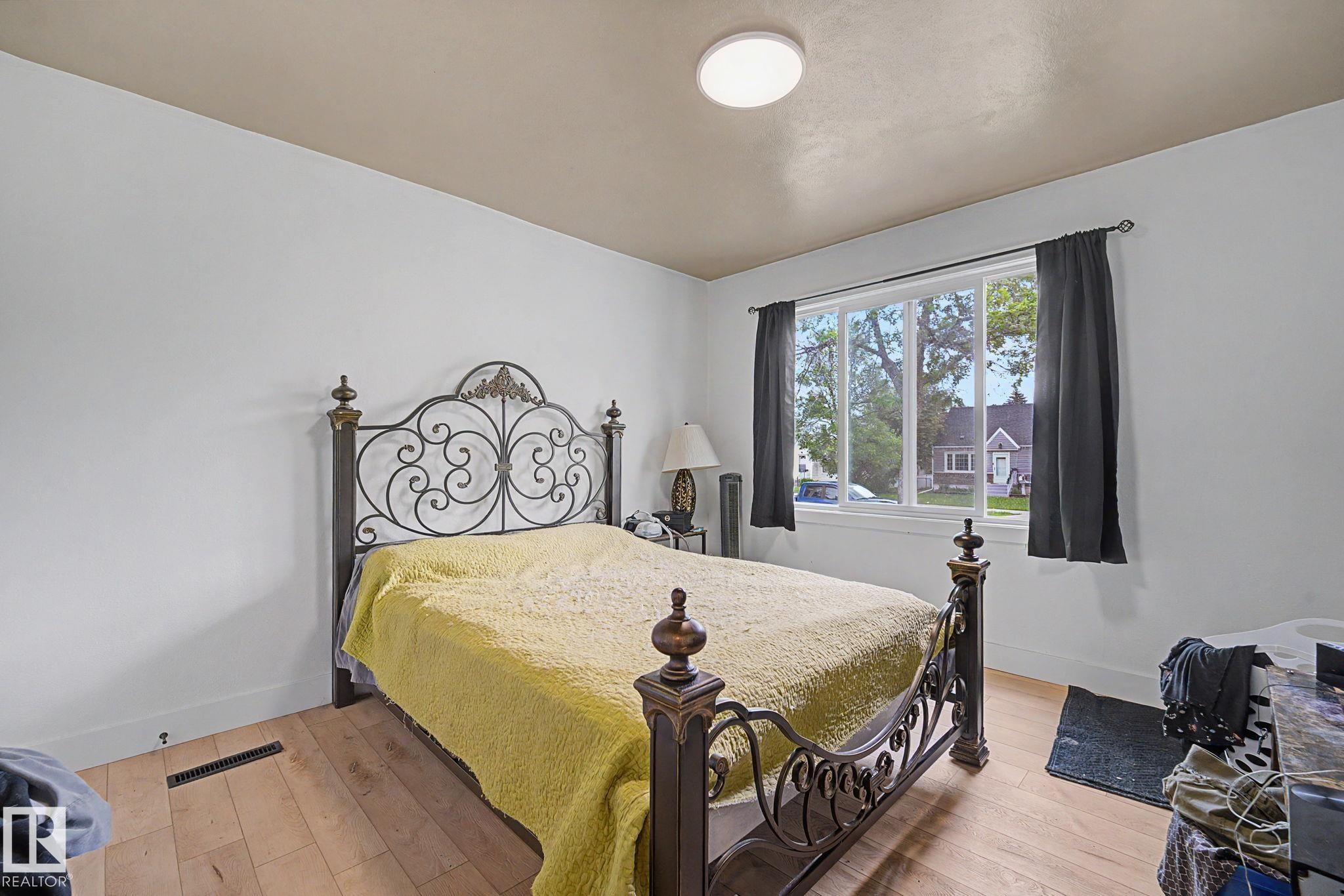 Bedroom featuring light wood-finish flooring and a large window with white trim - 11914 124 Street, Edmonton, AB