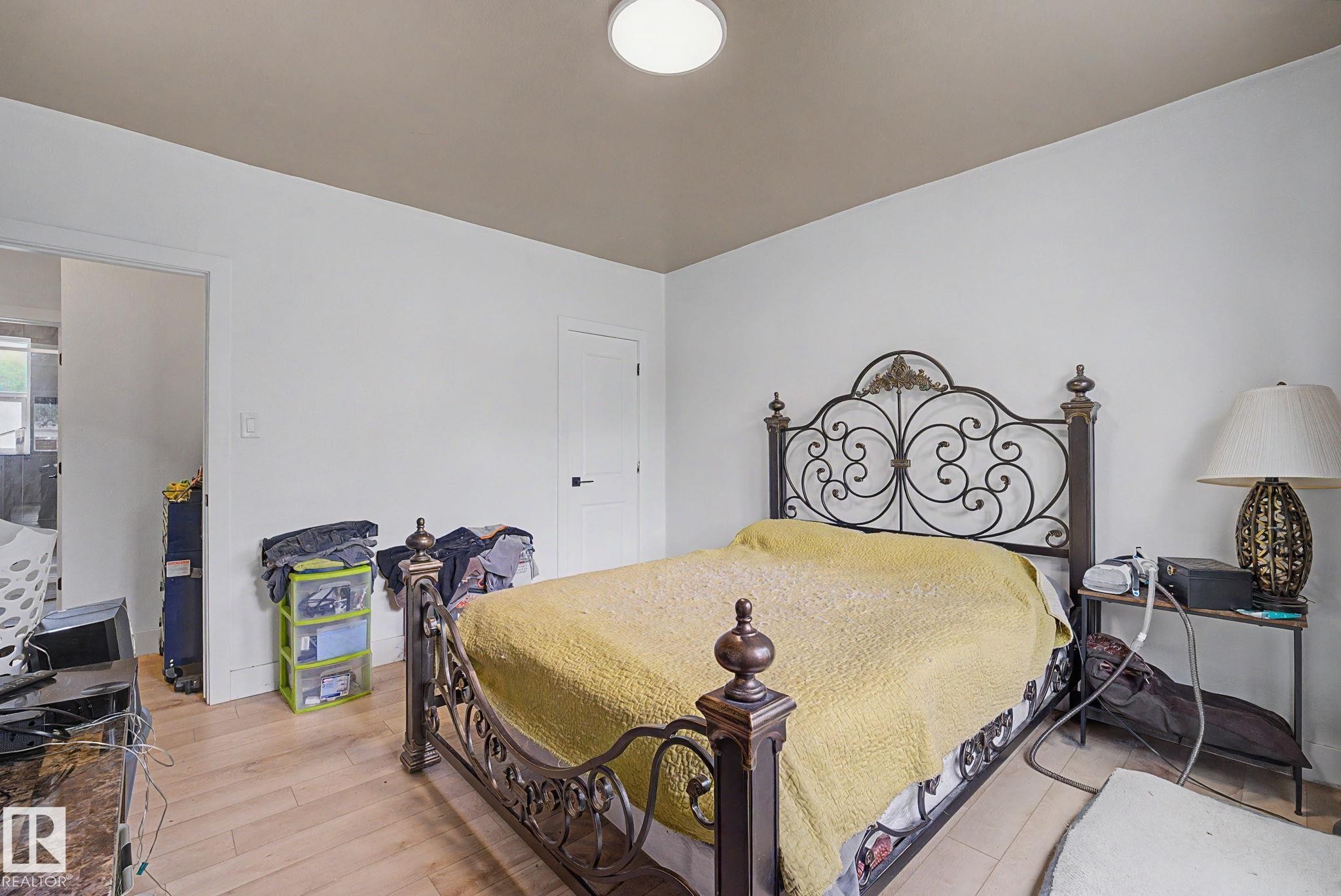 Hardwood-finish flooring throughout, featuring white walls, a contrasting ceiling, and a white interior door with dark hardware - 11914 124 Street, Edmonton, AB