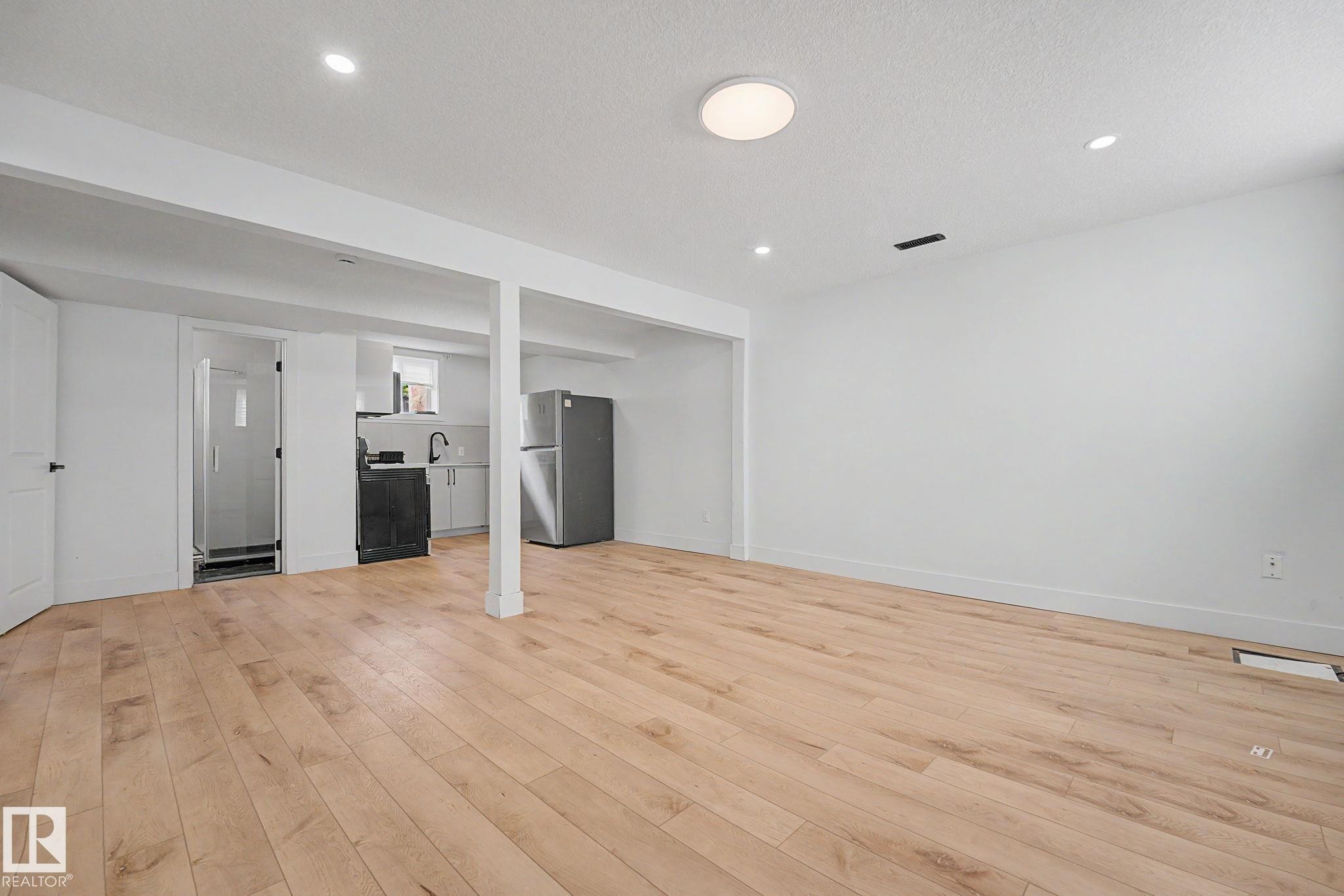 Open-concept living space featuring wood-finish flooring, recessed lighting, and a white color palette - 11914 124 Street, Edmonton, AB