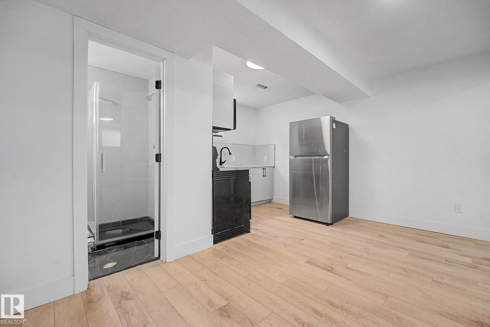 Kitchenette featuring a stainless steel refrigerator, white countertops, and dark lower cabinetry - 11914 124 Street, Edmonton, AB