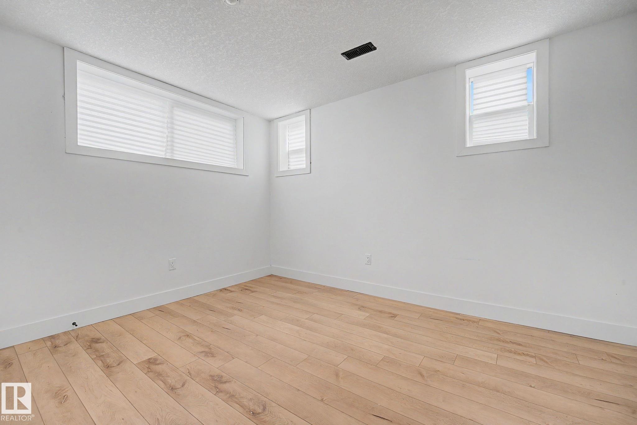 Bright room featuring wood-finish flooring, crisp white walls, and white trim - 11914 124 Street, Edmonton, AB