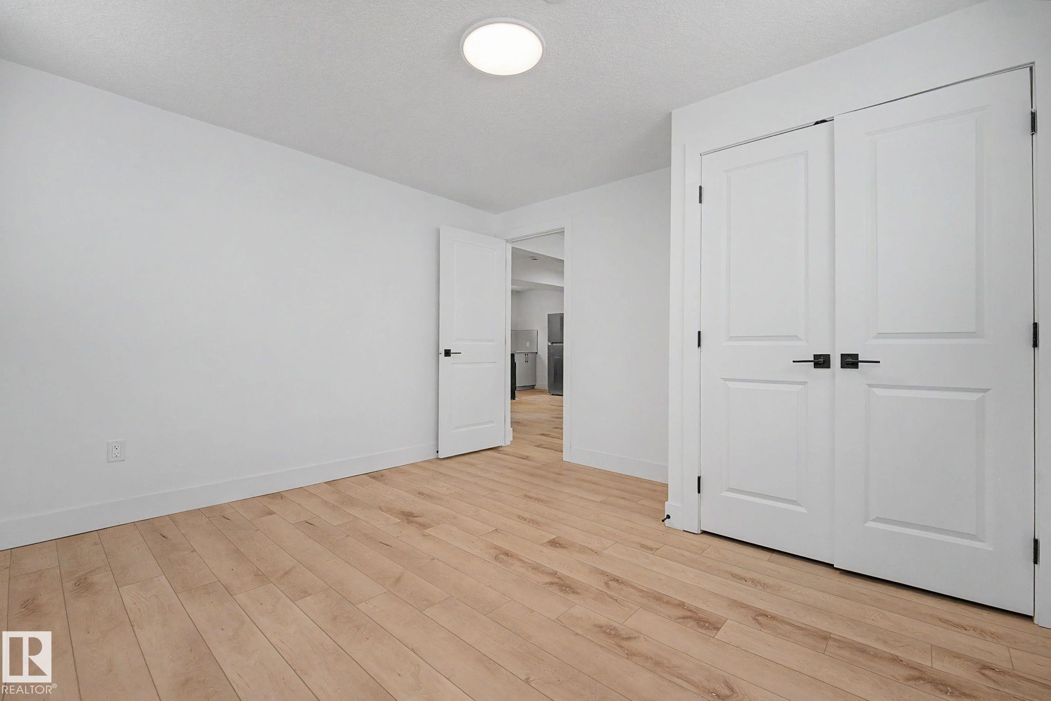 Room featuring light wood-finish flooring and white walls - 11914 124 Street, Edmonton, AB