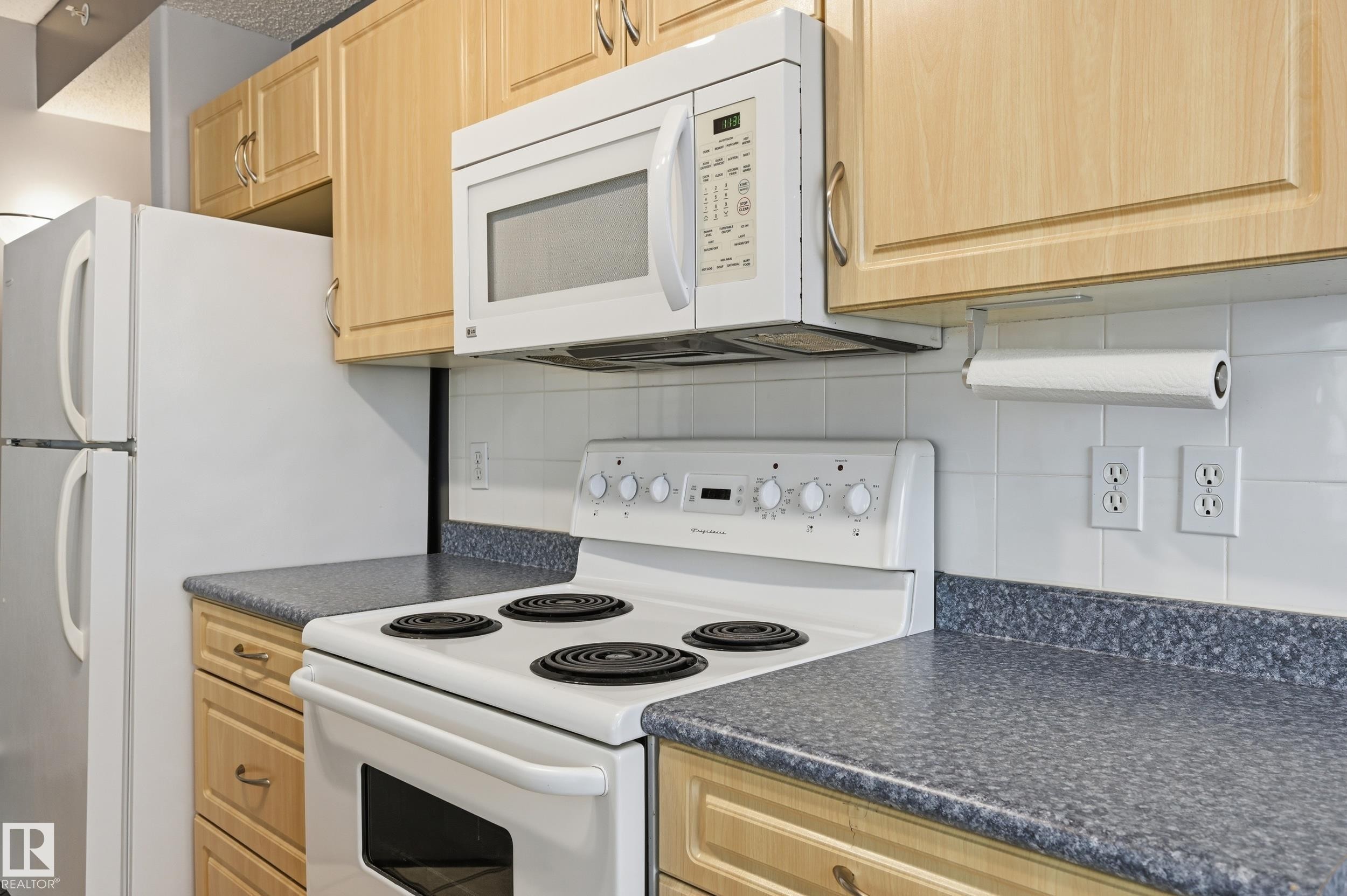 Kitchen featuring light wood-finish cabinetry, a white electric range, and a built-in microwave - 203 11103 84 Avenue, Edmonton, AB