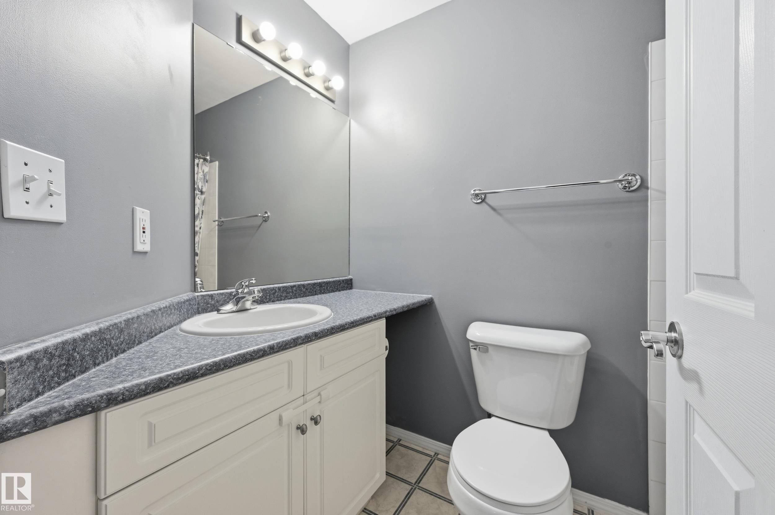 Bathroom featuring a vanity with an integrated sink, a speckled countertop, and white cabinetry with chrome hardware - 203 11103 84 Avenue, Edmonton, AB